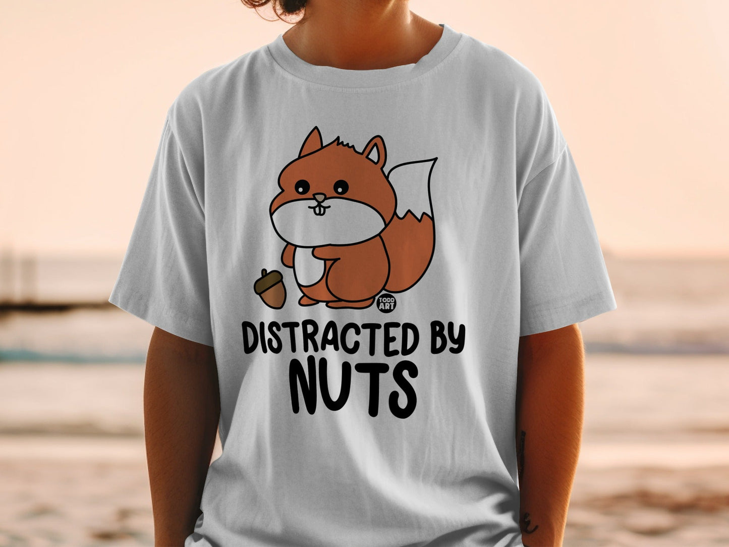 Distracted by Nuts text with cartoon squirrel holding acorn on t-shirt.
