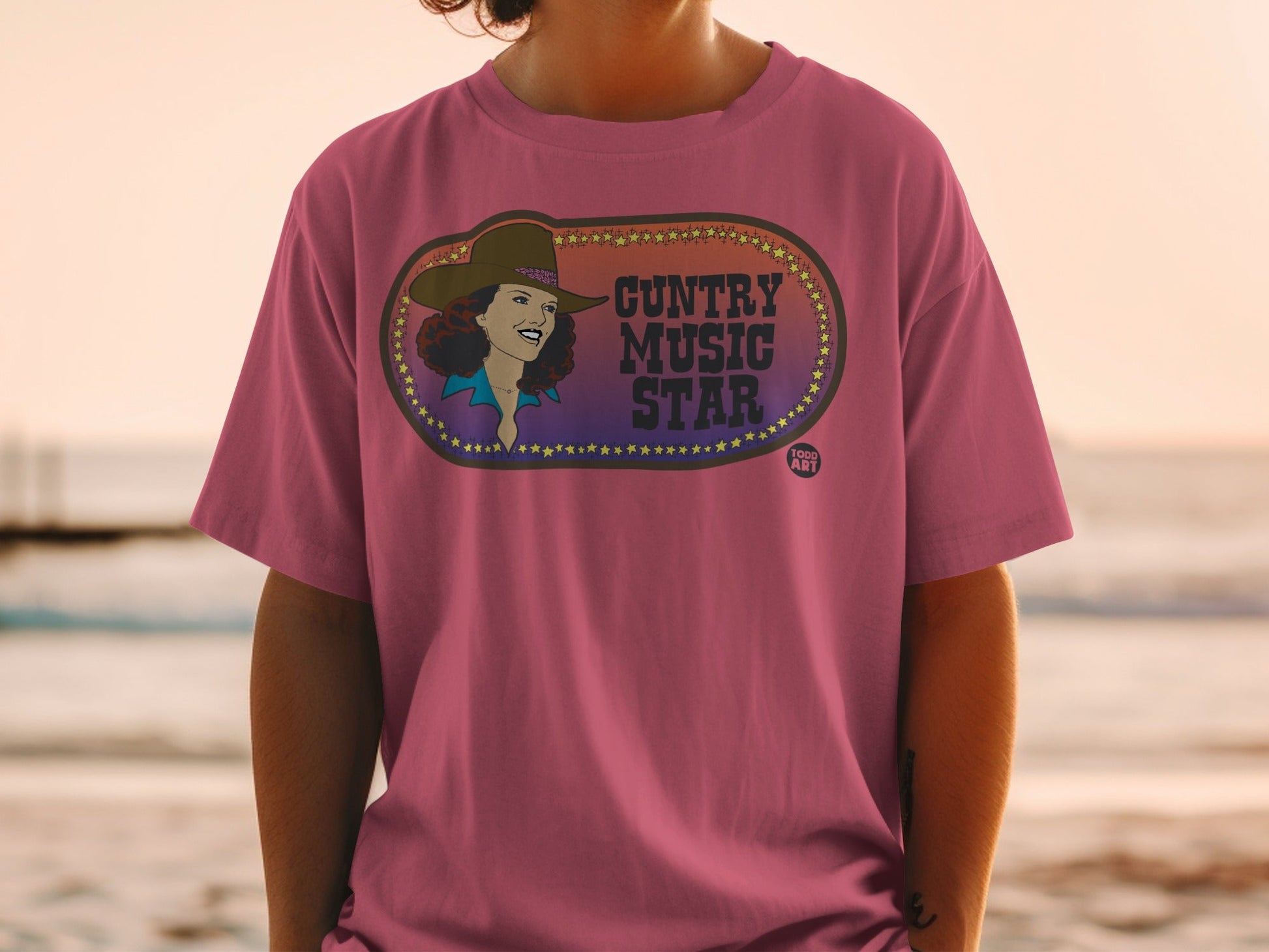 Woman wearing a pink t-shirt with a "Country Music Star" graphic.