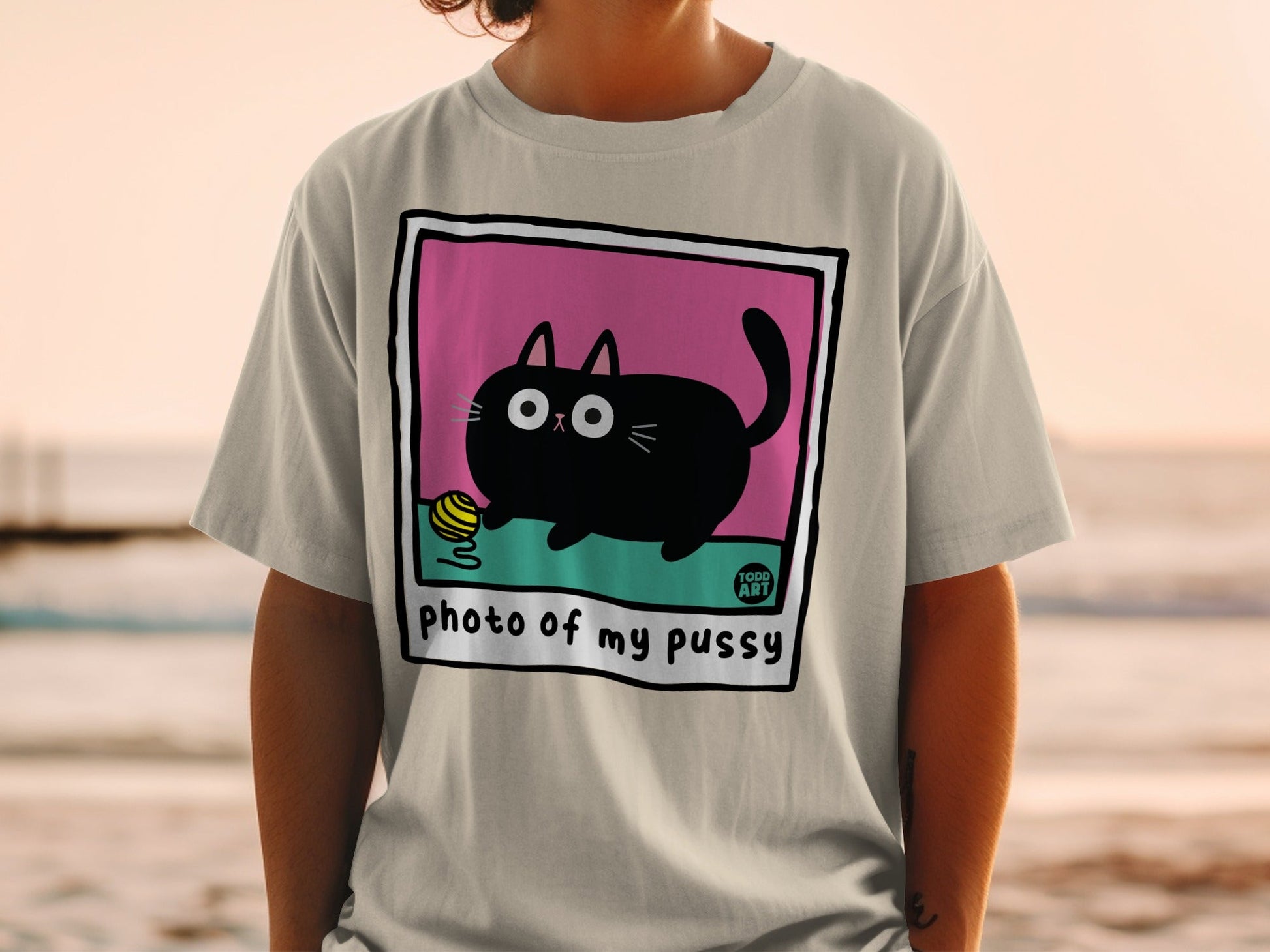 Black cat with yellow yarn ball on a t-shirt reading "photo of my pussy".