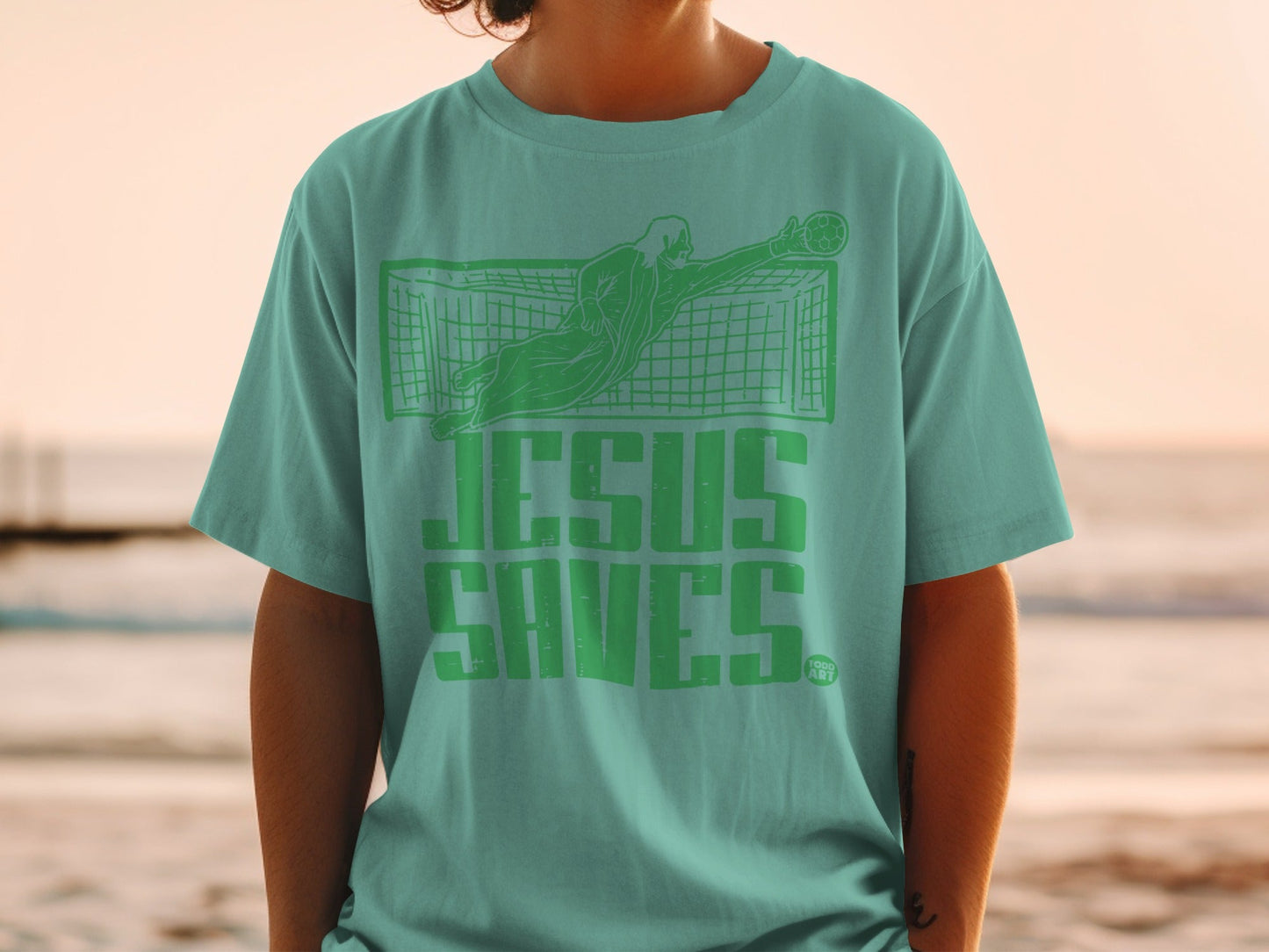 Teal t-shirt with "JESUS SAVES" graphic and soccer goalie.