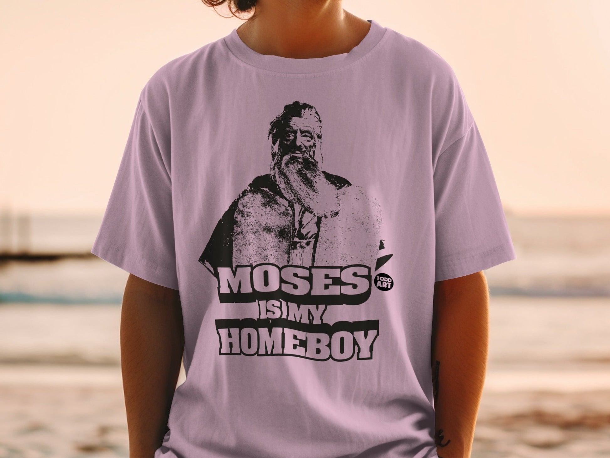 Purple t-shirt with a black graphic of Moses and text "MOSES IS MY HOMEBOY".