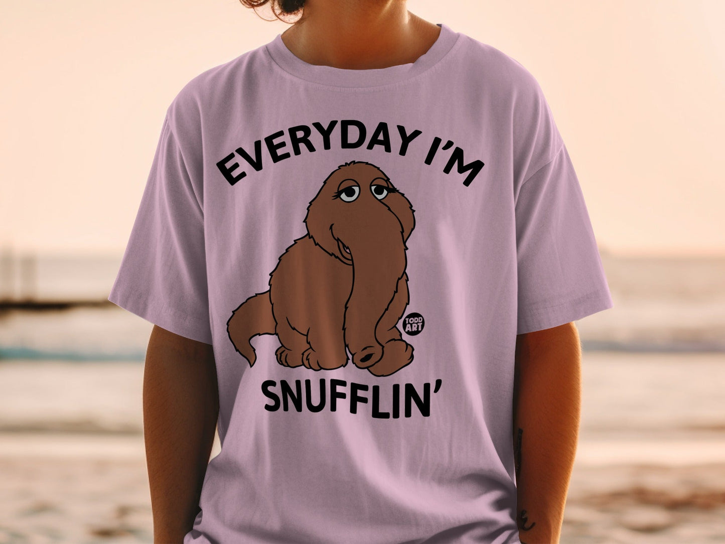 Lavender t-shirt with graphic of a brown furry creature and text "EVERYDAY I'M SNUFFLIN'".