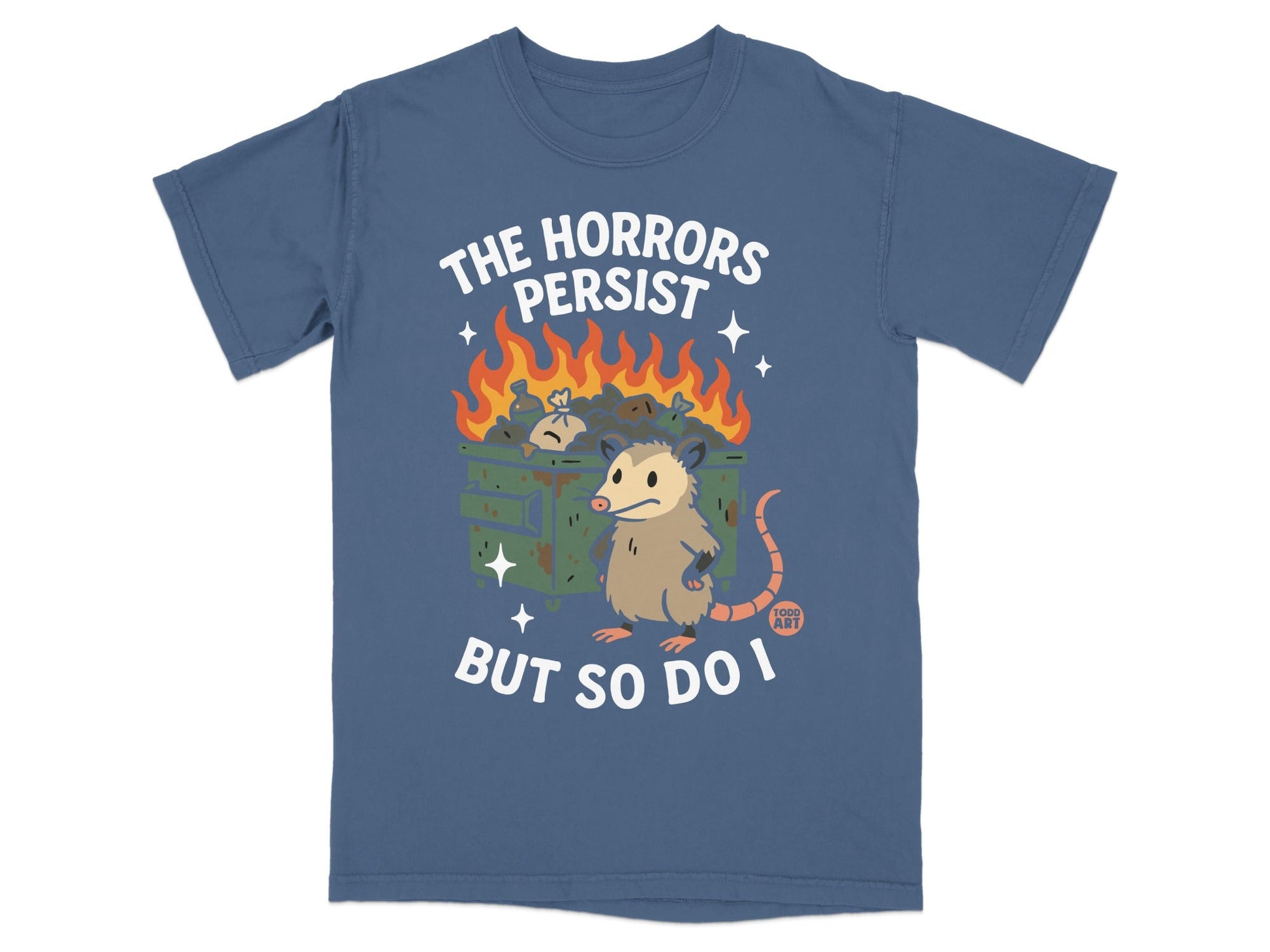 T-shirt with possum near dumpster fire, "The Horrors Persist But So Do I" text.