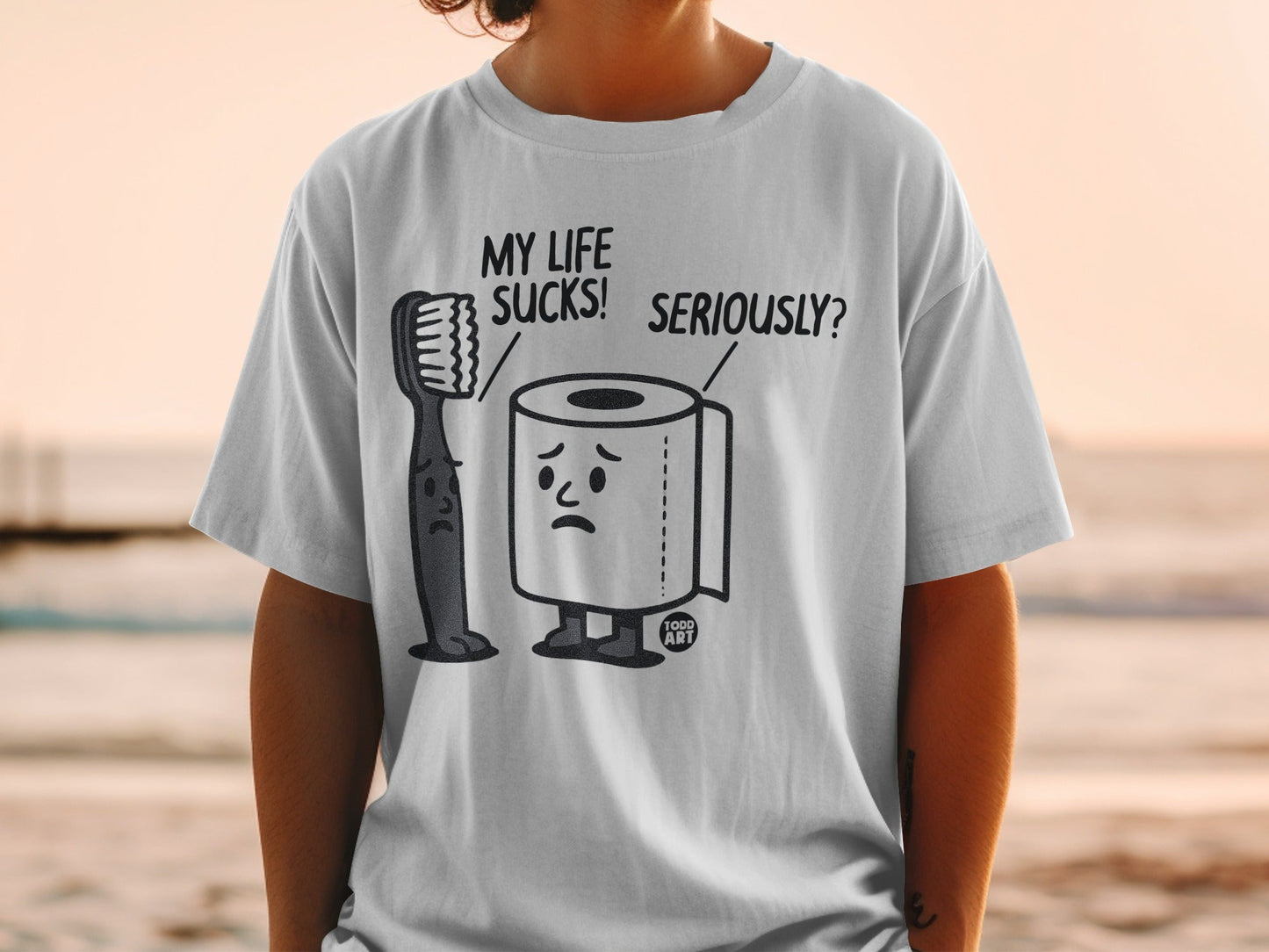T-shirt with cartoon toothbrush and toilet paper characters saying "My life sucks! Seriously?".