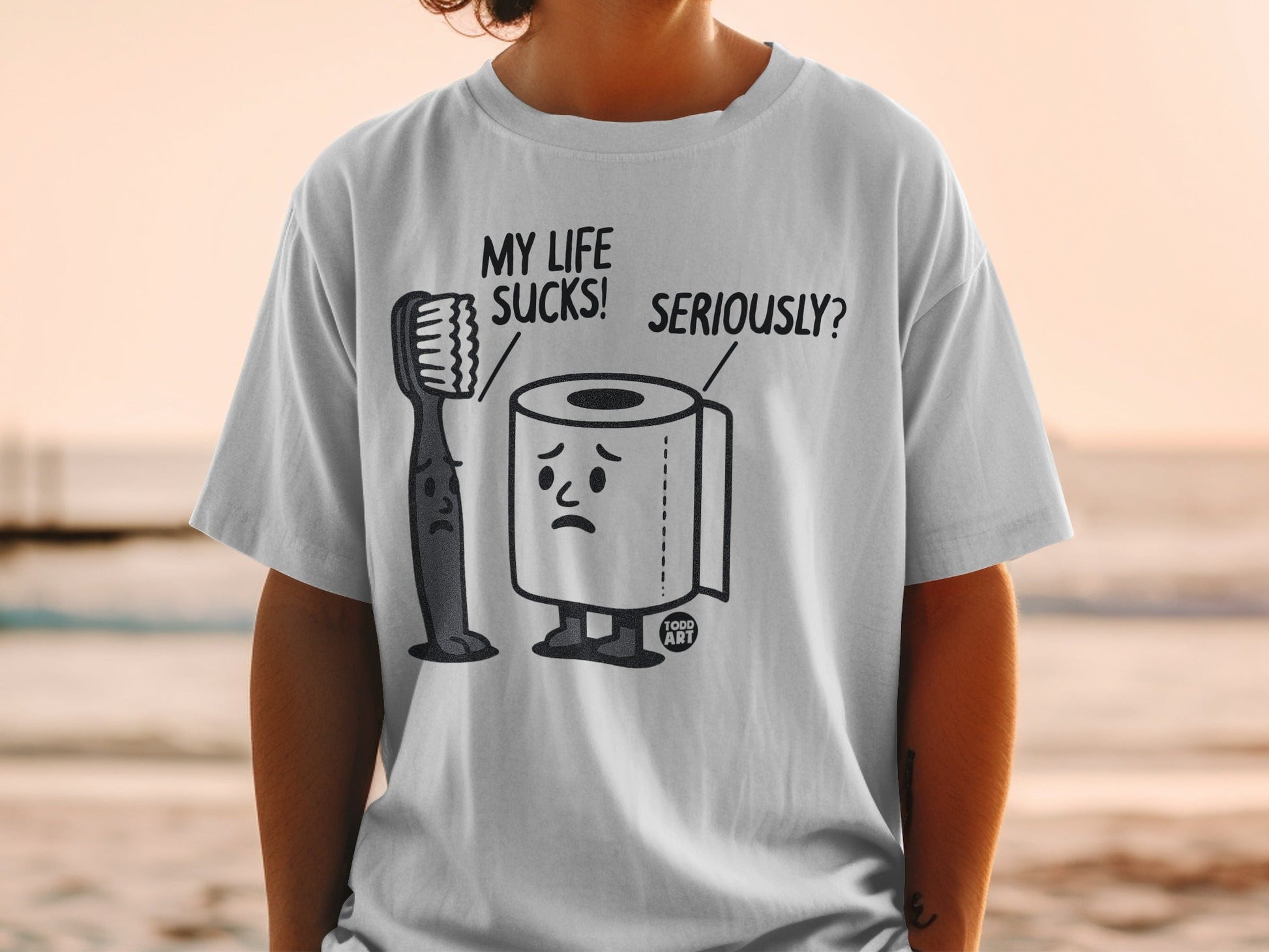 T-shirt with cartoon toothbrush and toilet paper characters saying "My life sucks! Seriously?".