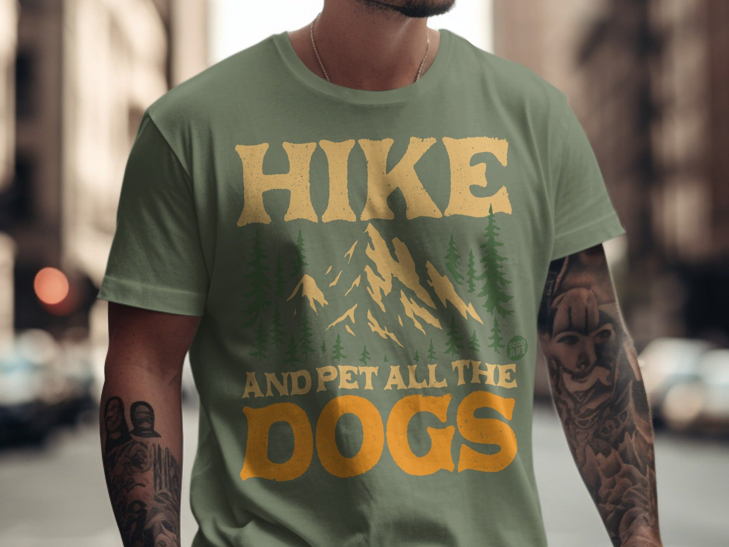 Green t-shirt with text "Hike and pet all the dogs" and mountain graphic.