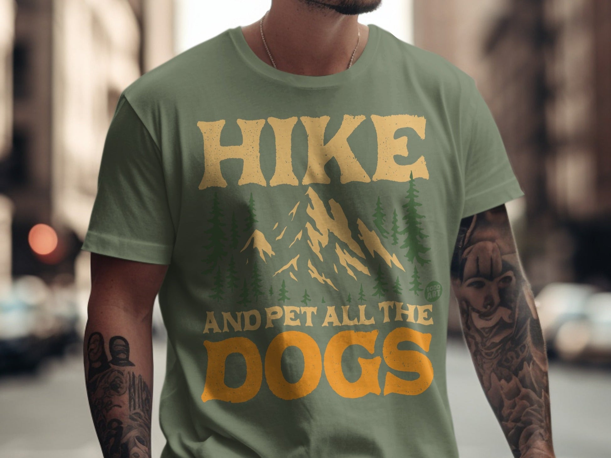 Green t-shirt with text "Hike and pet all the dogs" and mountain graphic.