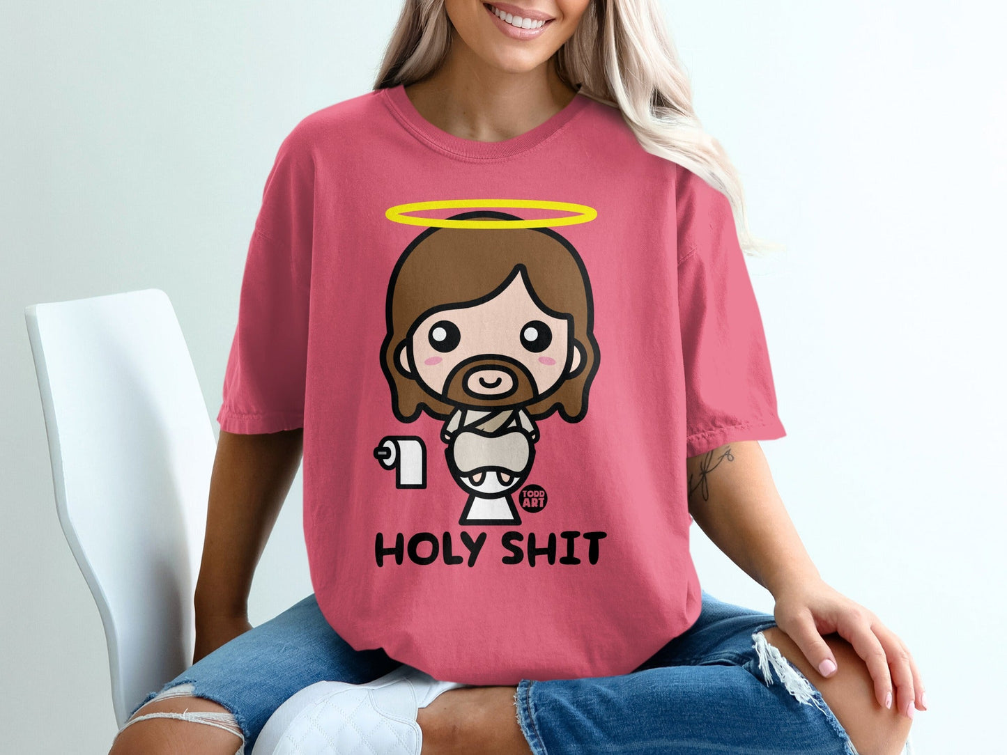 Pink t-shirt with cartoon Jesus holding toilet paper, text reads "HOLY SHIT".