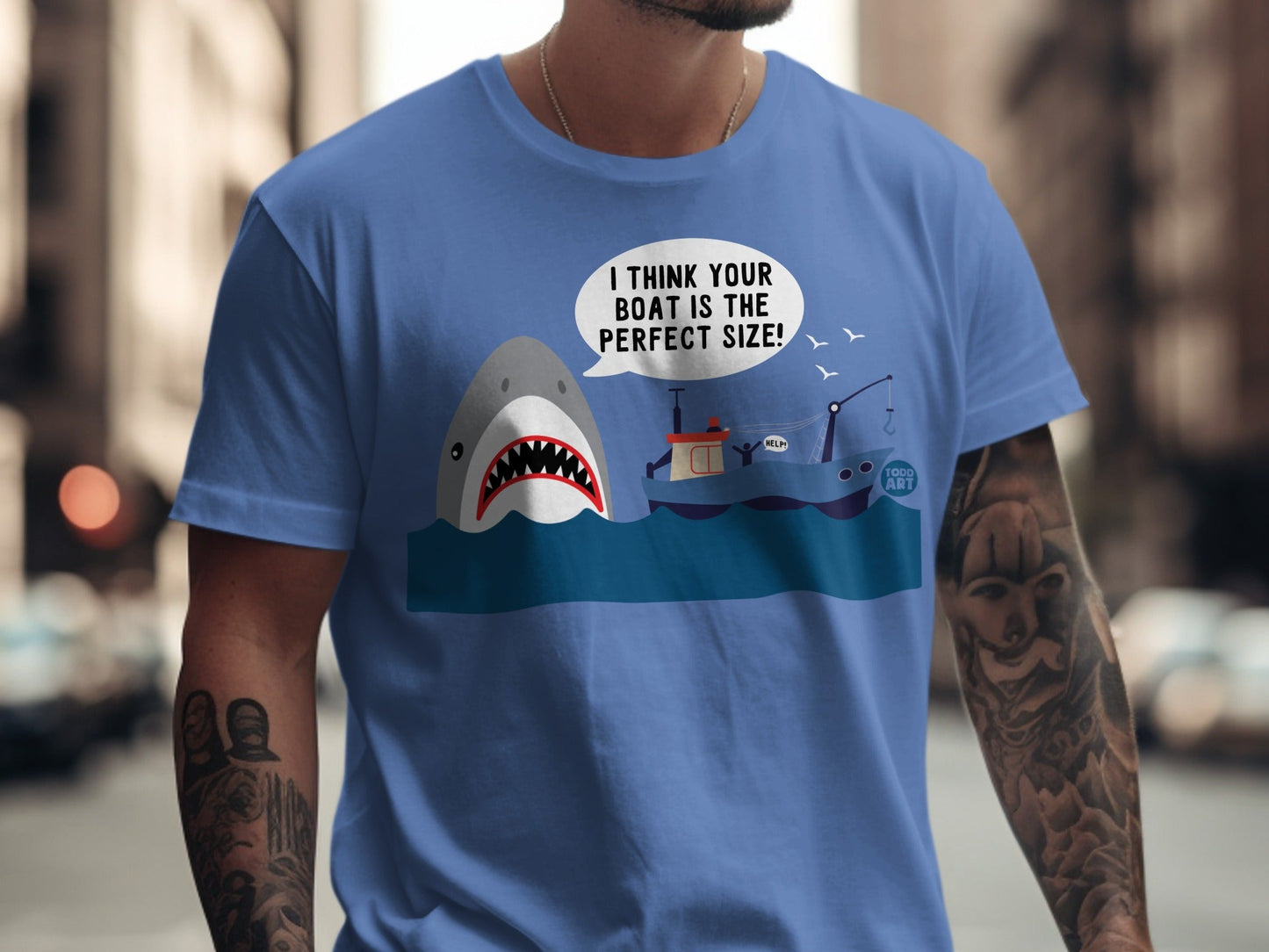 T-shirt with a cartoon shark looking at a boat, text reads "I THINK YOUR BOAT IS THE PERFECT SIZE!"