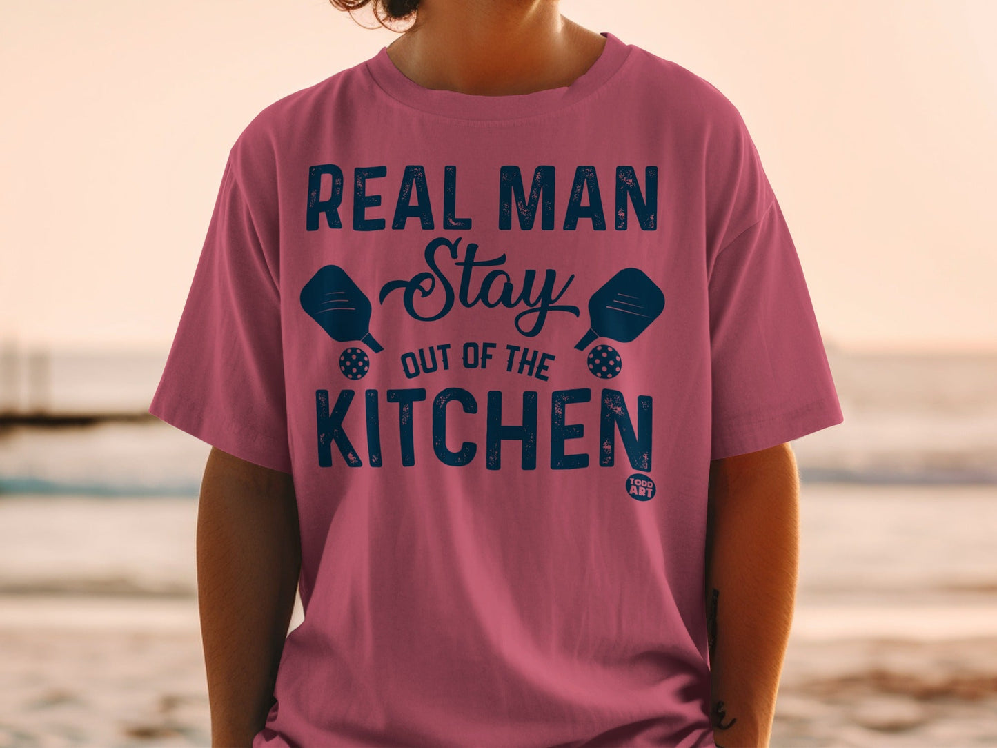 Pink t-shirt with blue text and pickleball paddles.