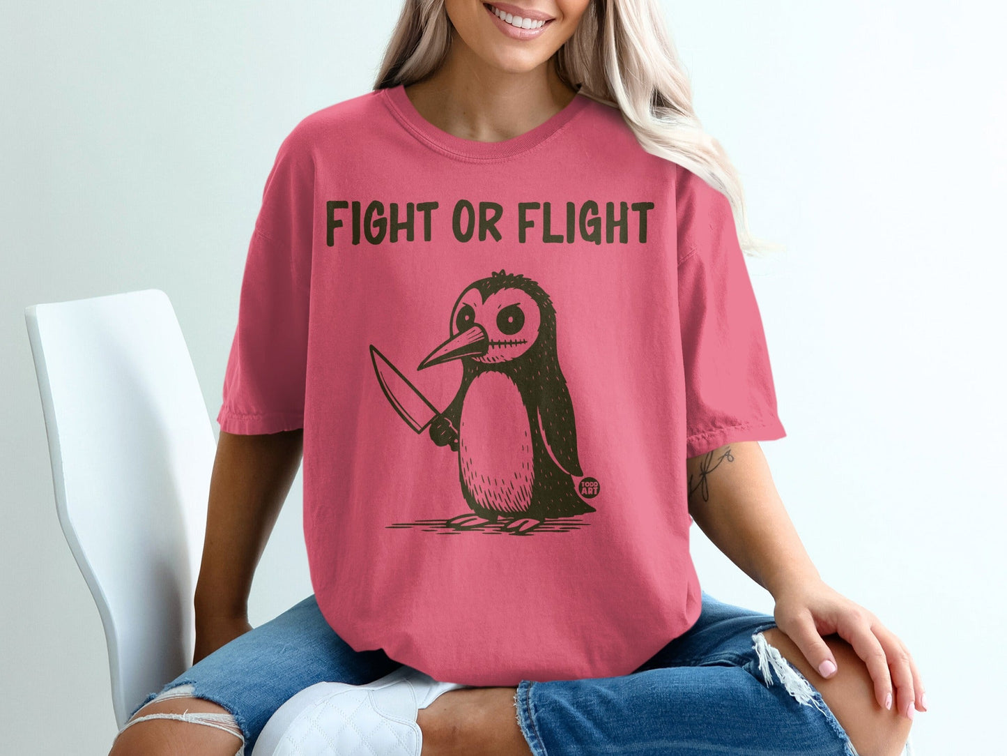Penguin with knife and text "FIGHT OR FLIGHT" on a pink t-shirt.