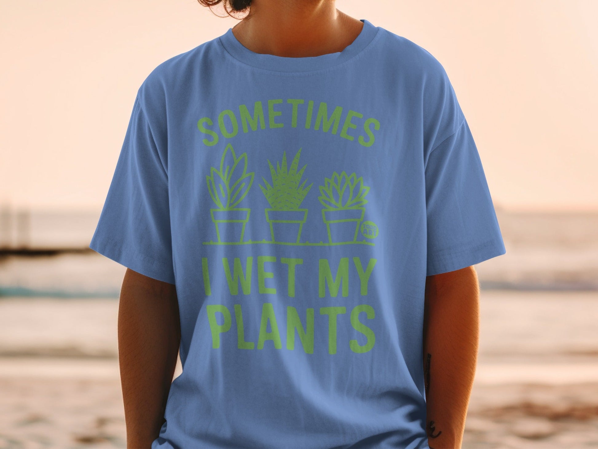 Blue t-shirt with green text "SOMETIMES I WET MY PLANTS" and plant graphics.