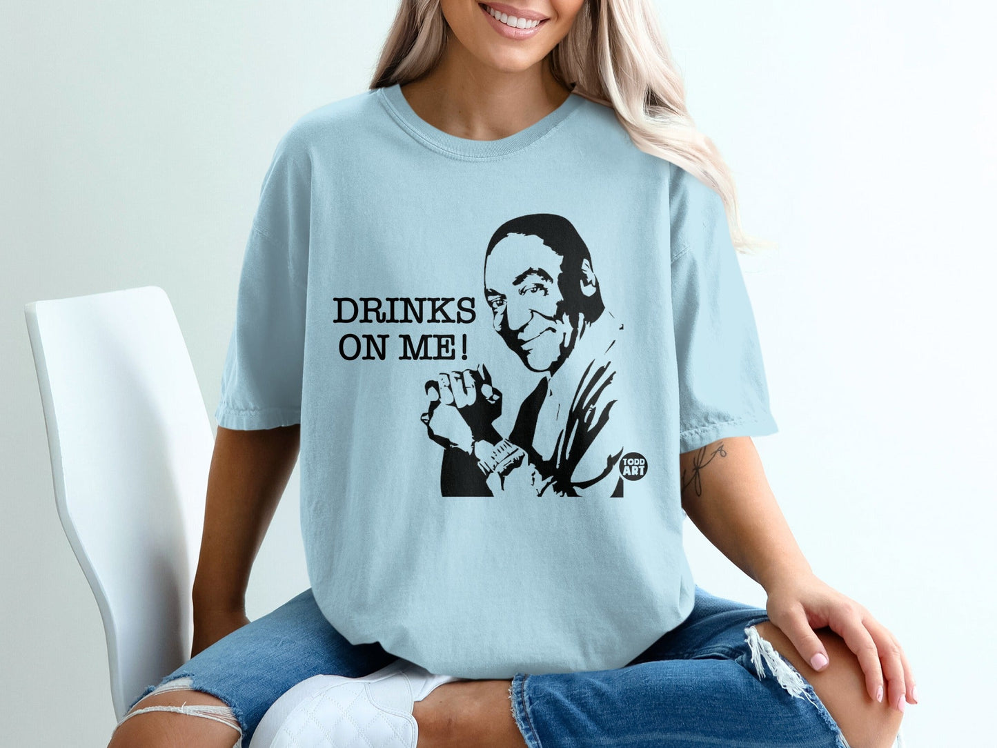 Light blue t-shirt with black graphic of a man and text "DRINKS ON ME!".