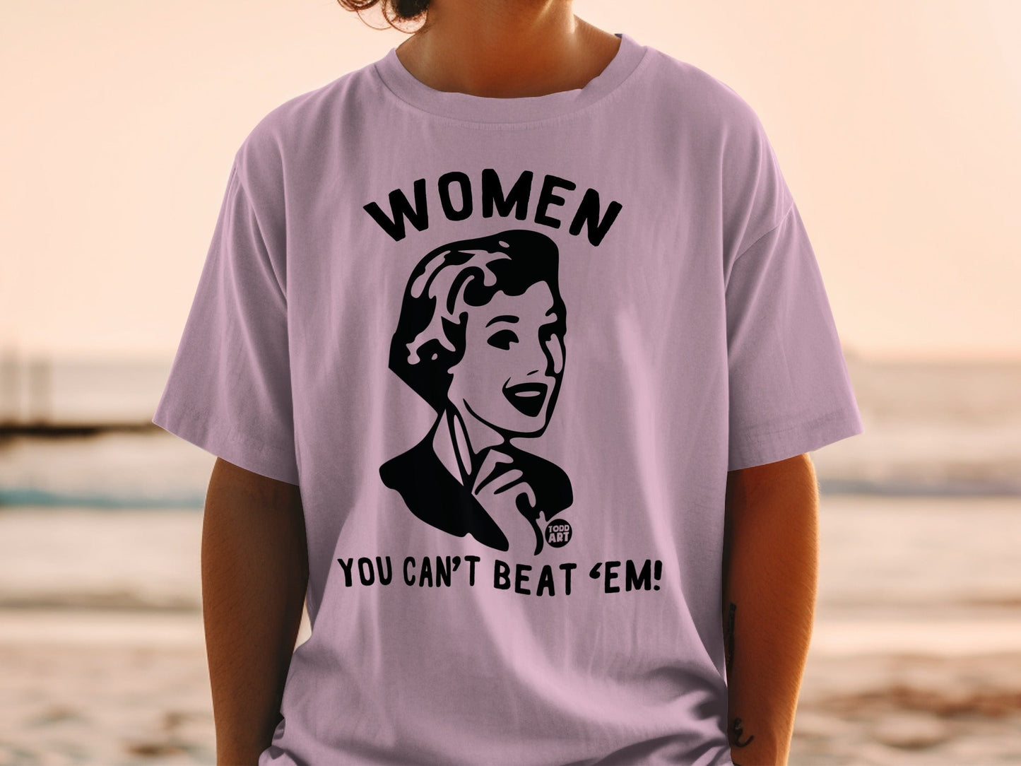 Purple t-shirt with black graphic of a woman and text "WOMEN YOU CAN'T BEAT 'EM!".