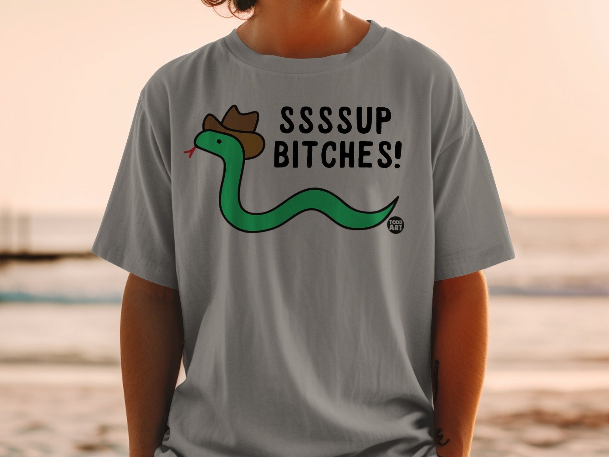 Gray t-shirt with green snake wearing cowboy hat, saying "SSSSUP BITCHES!".