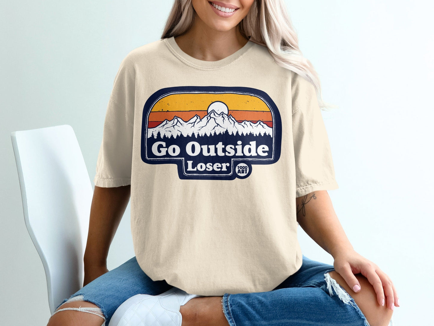 Cream t-shirt with "Go Outside Loser" mountain sunset graphic.