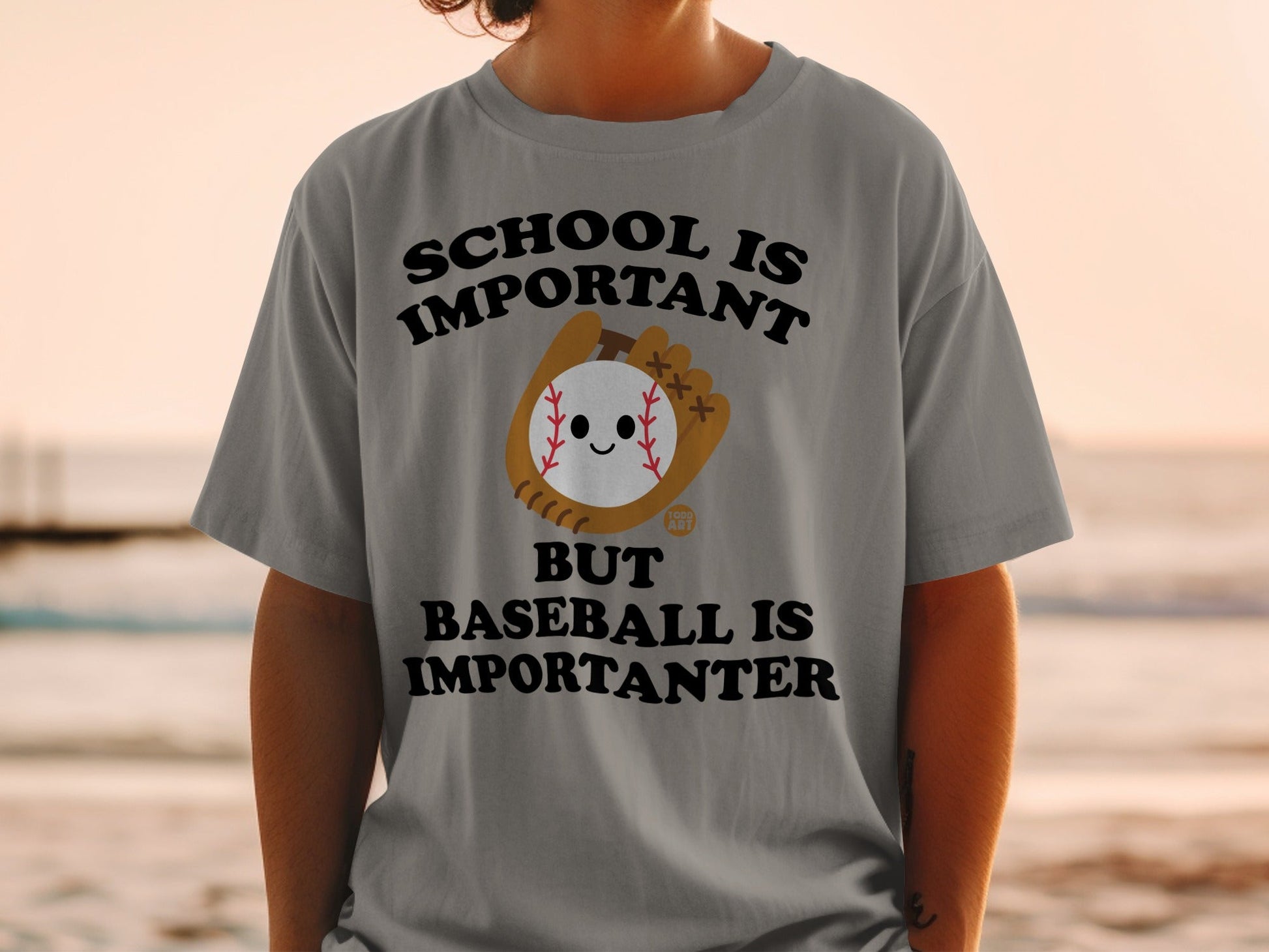 Gray t-shirt with "School is important but baseball is importanter" and cartoon baseball.
