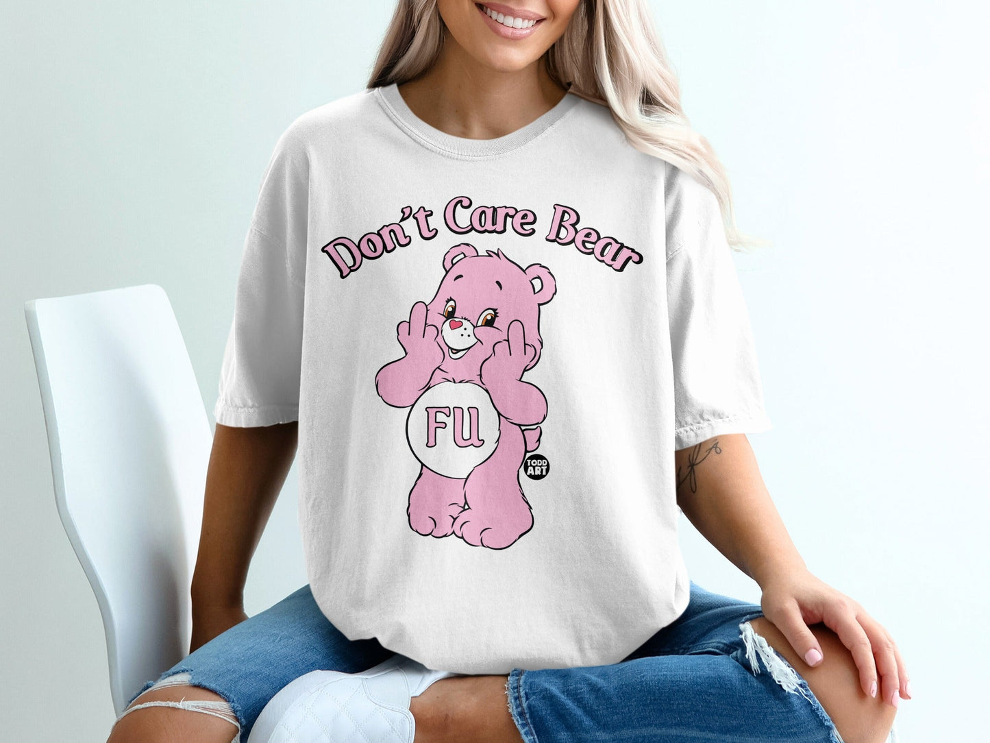 Pink bear graphic on white t-shirt with "Don't Care Bear" text and middle finger gesture.
