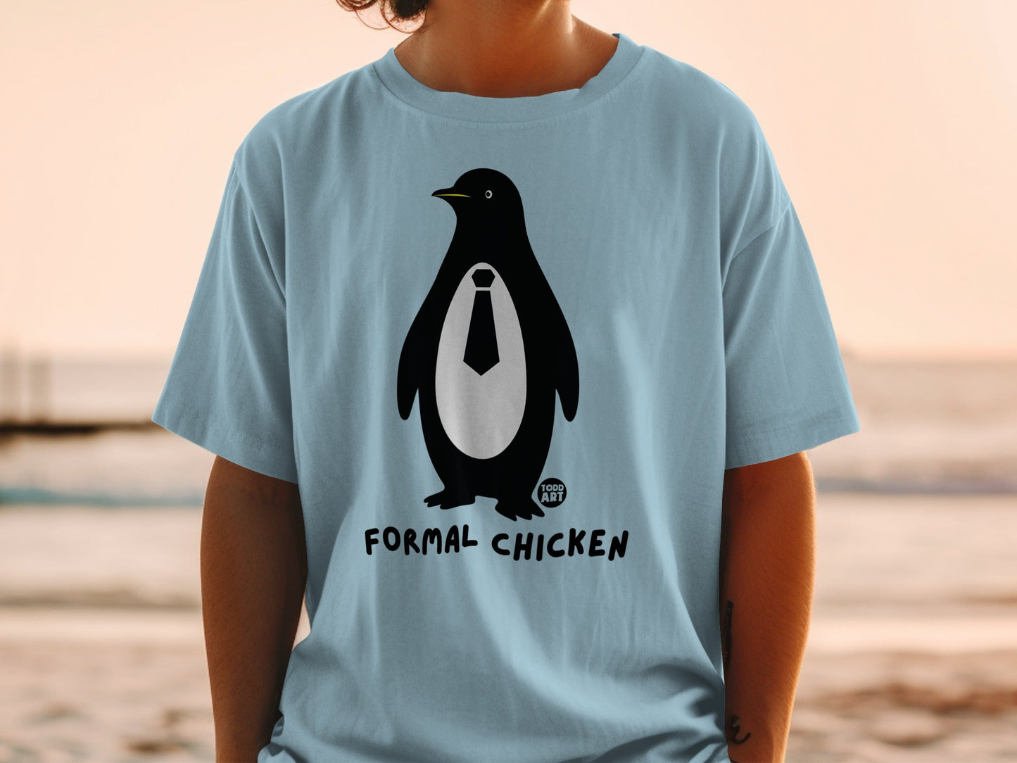 Light blue t-shirt with a penguin wearing a tie and the words "TODD ART FORMAL CHICKEN".
