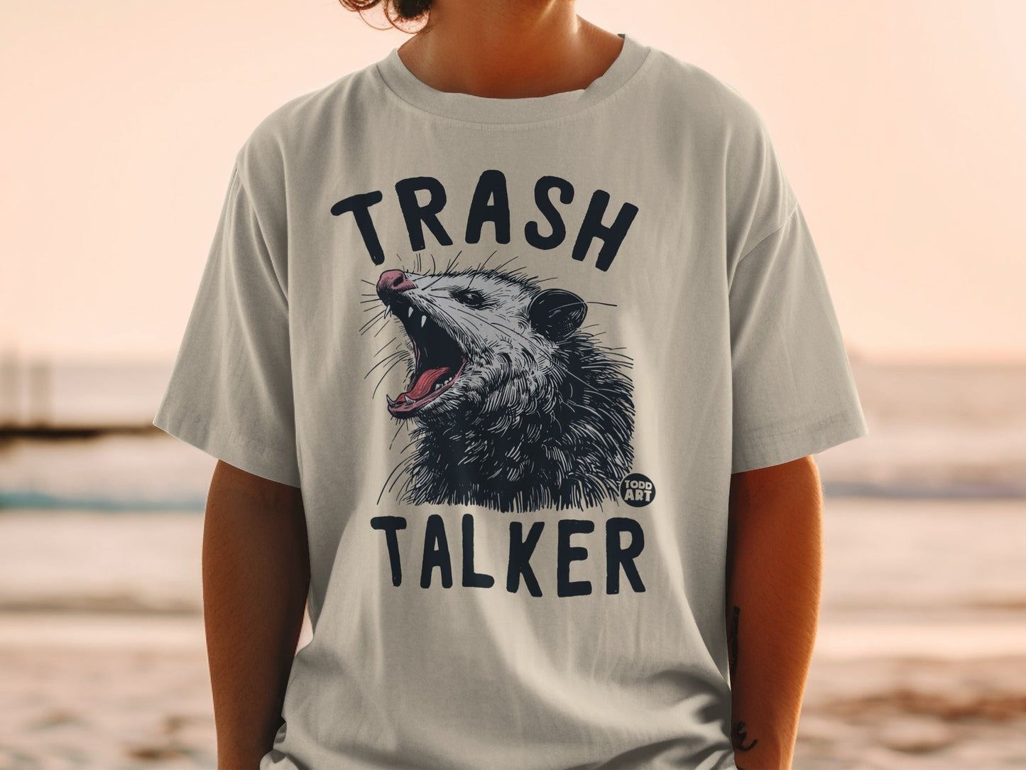 T-shirt with a graphic of an opossum mid-yawn with "TRASH TALKER" text.