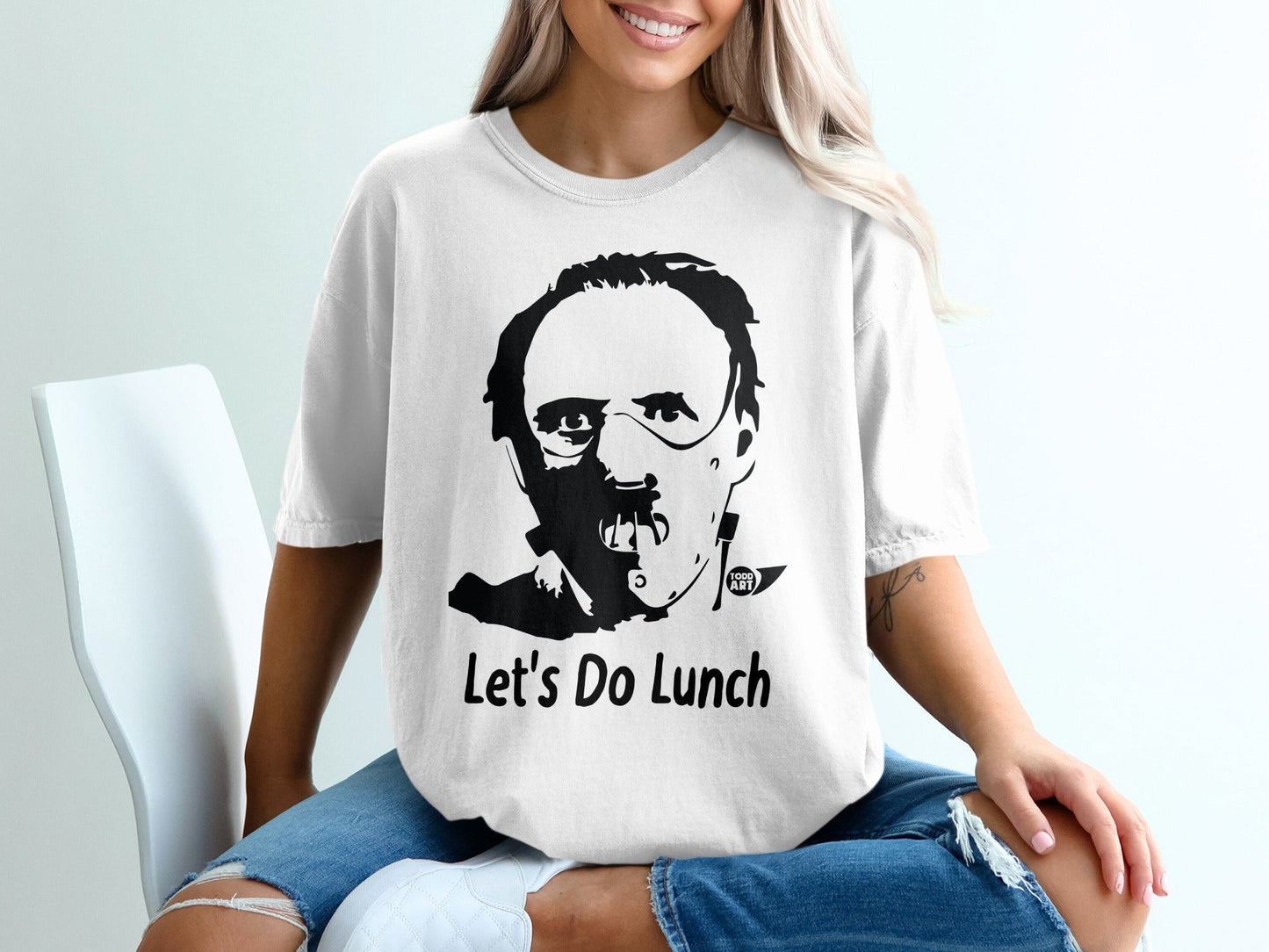White t-shirt with black graphic of Hannibal Lecter and text "Let's Do Lunch".