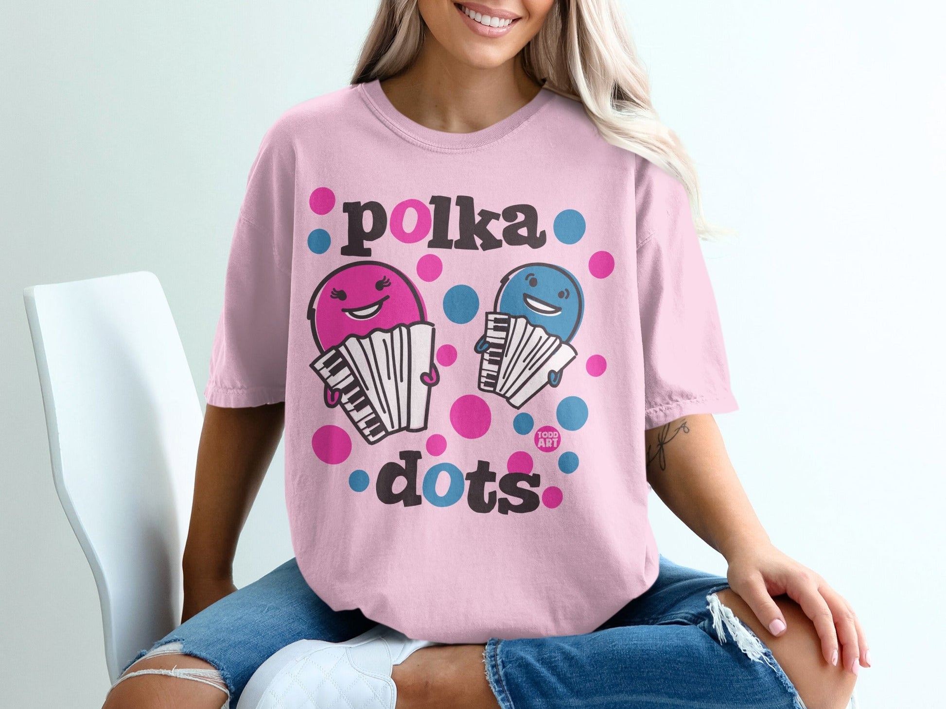Pink t-shirt with cartoon accordions and polka dots text.