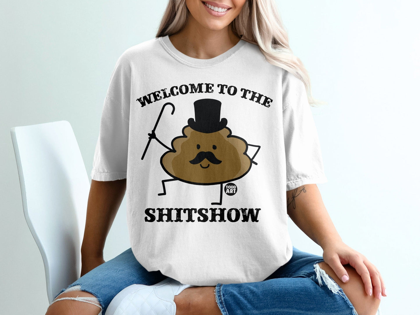 White t-shirt with "Welcome to the Shitshow" text and a cartoon poop character.