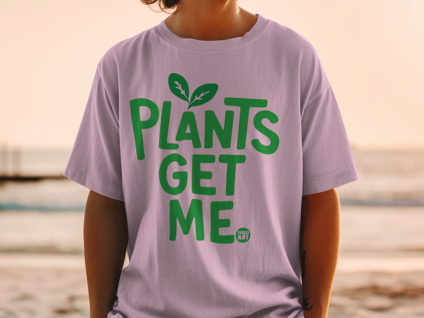 Light purple t-shirt with green text "PLANTS GET ME" and a small leaf logo.