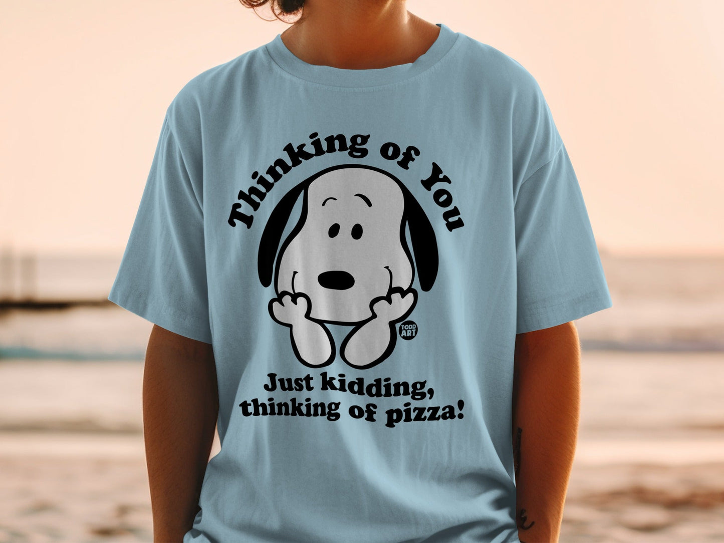 Light blue t-shirt with Snoopy saying "Just kidding, thinking of pizza!"