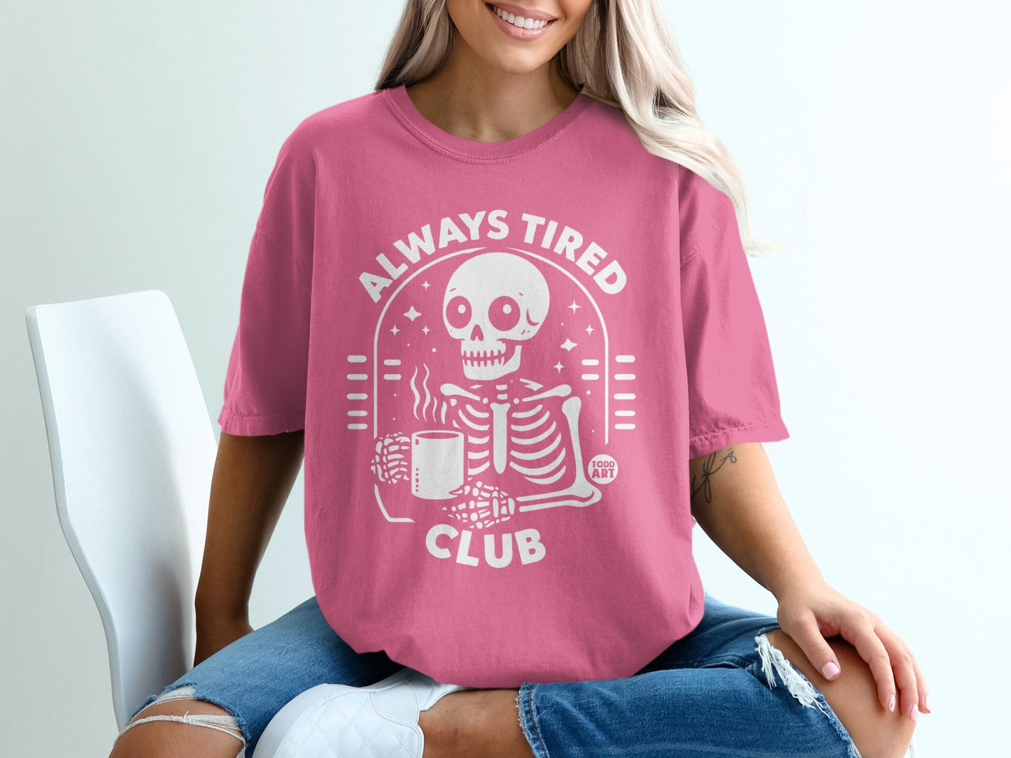 Pink t-shirt with white "Always Tired Club" text and skeleton graphic.