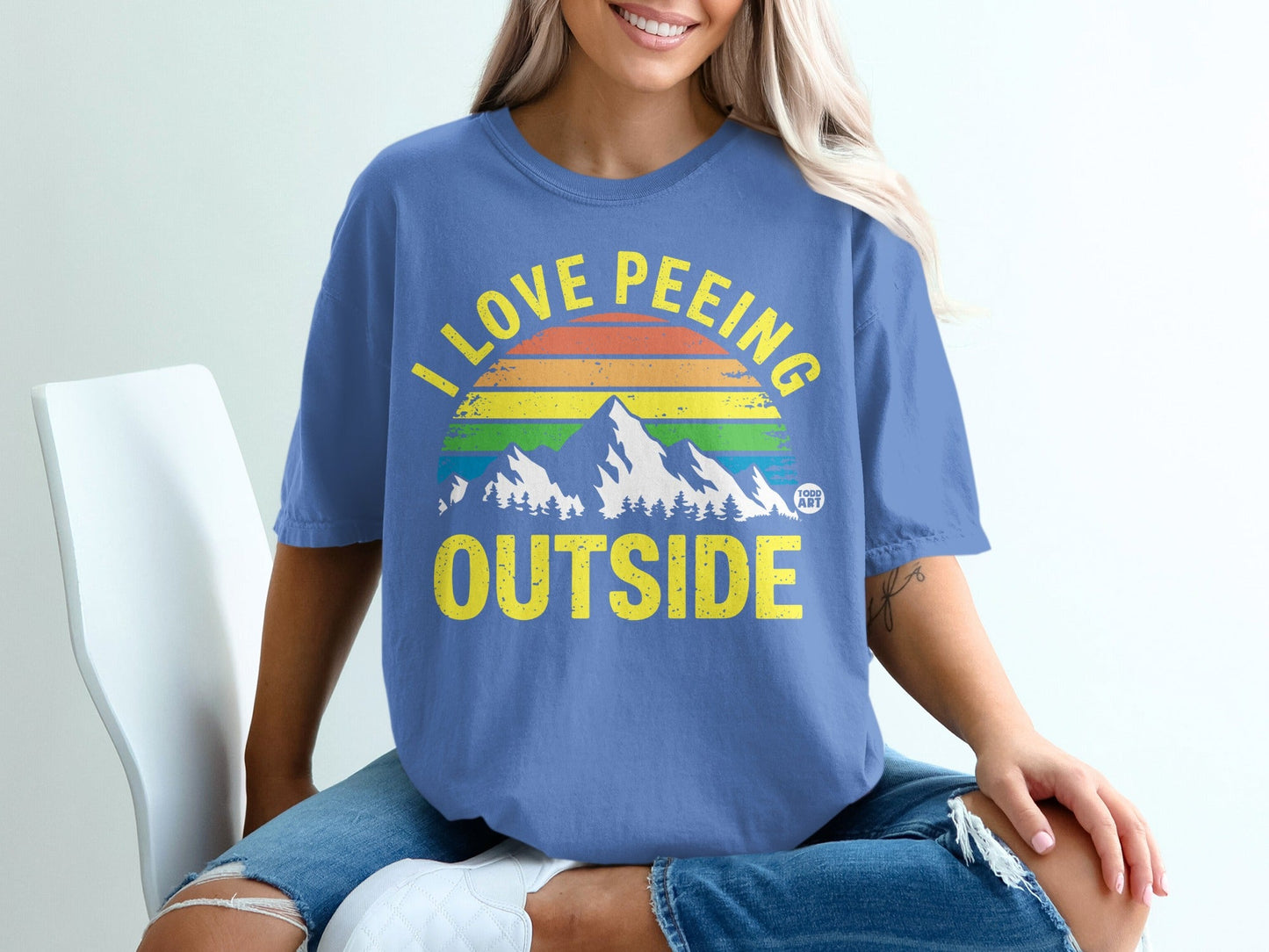 Blue t-shirt with rainbow mountains and text "I love peeing outside."