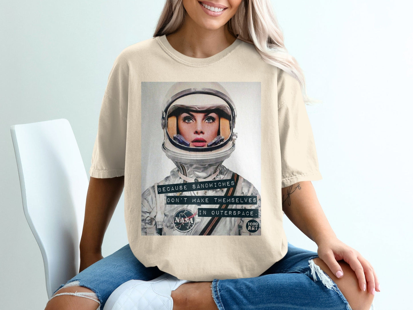 Woman wearing a cream t-shirt with NASA astronaut graphic and text.