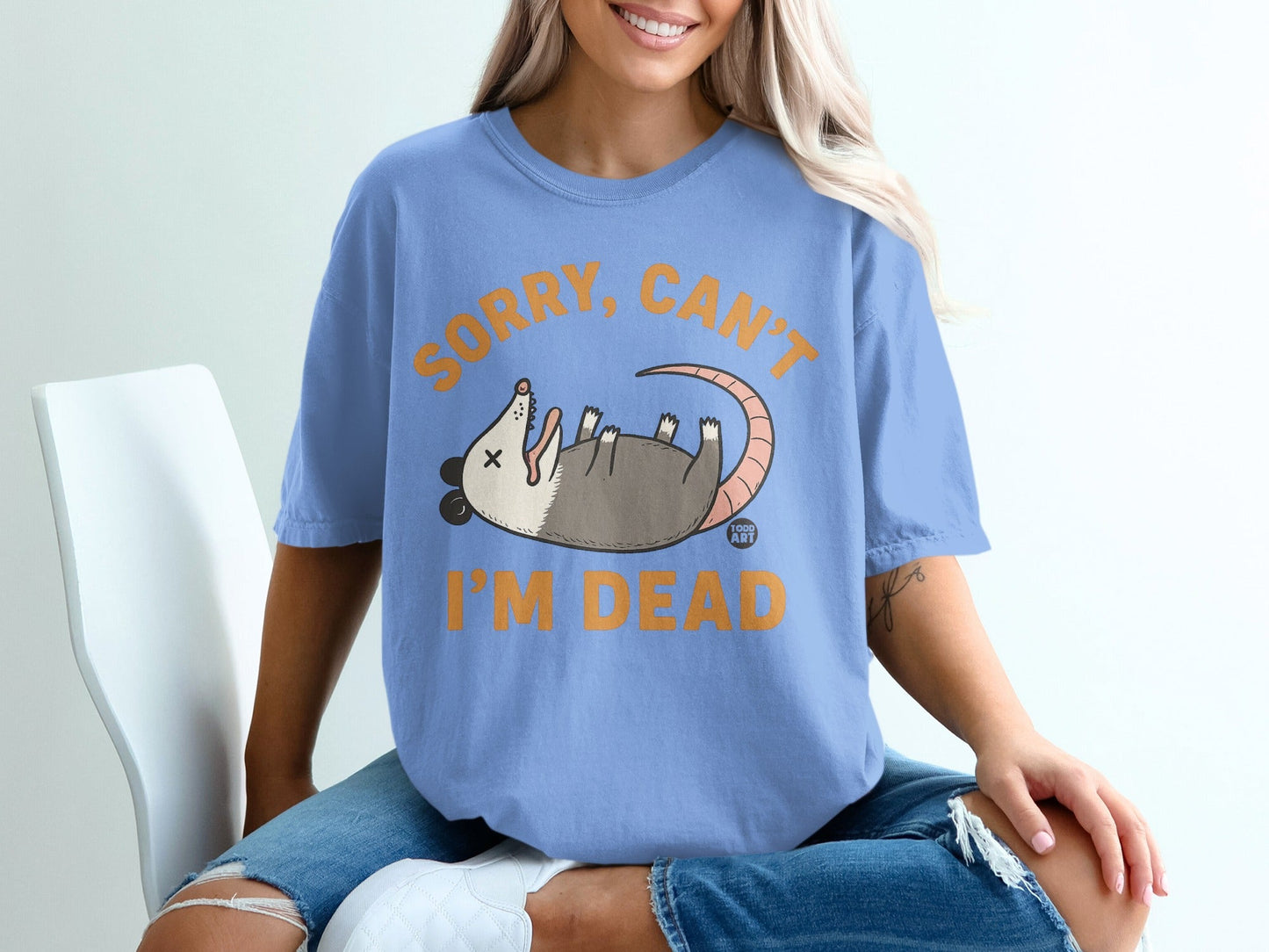 Light blue t-shirt with an illustration of a dead opossum and text reading "Sorry, can't I'm dead".