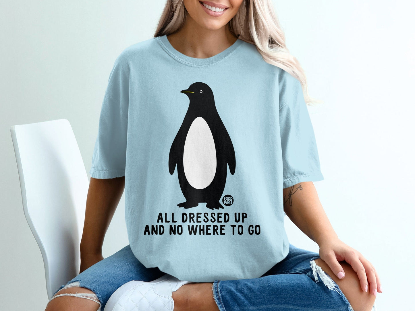 Light blue t-shirt with a penguin graphic and text that says "ALL DRESSED UP AND NO WHERE TO GO".