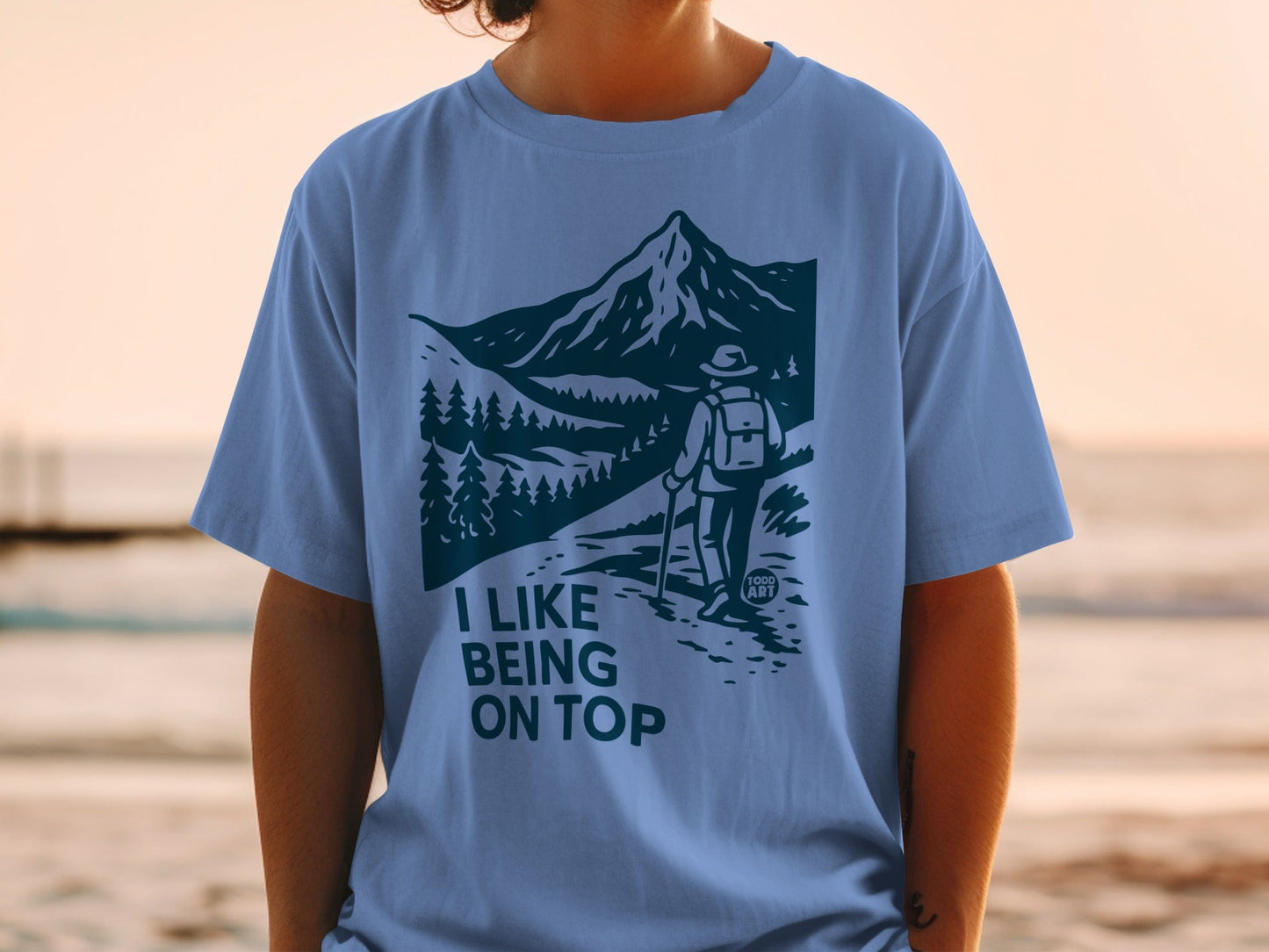 Light blue t-shirt with "I LIKE BEING ON TOP" mountain hiking graphic.