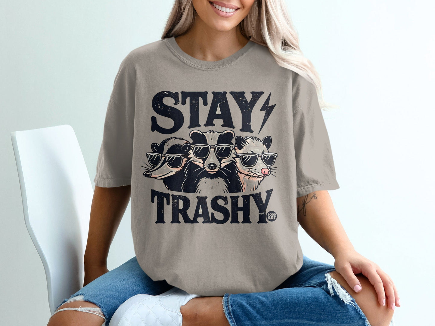 T-shirt with "STAY TRASHY" and three raccoons wearing sunglasses.