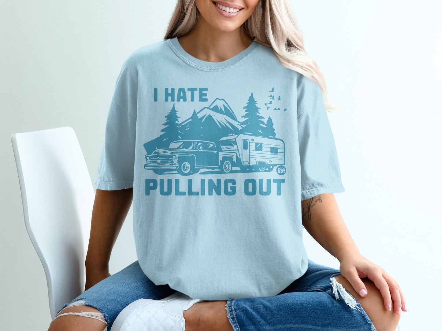 T-shirt with graphic of mountains, trees, and a truck towing a camper.
