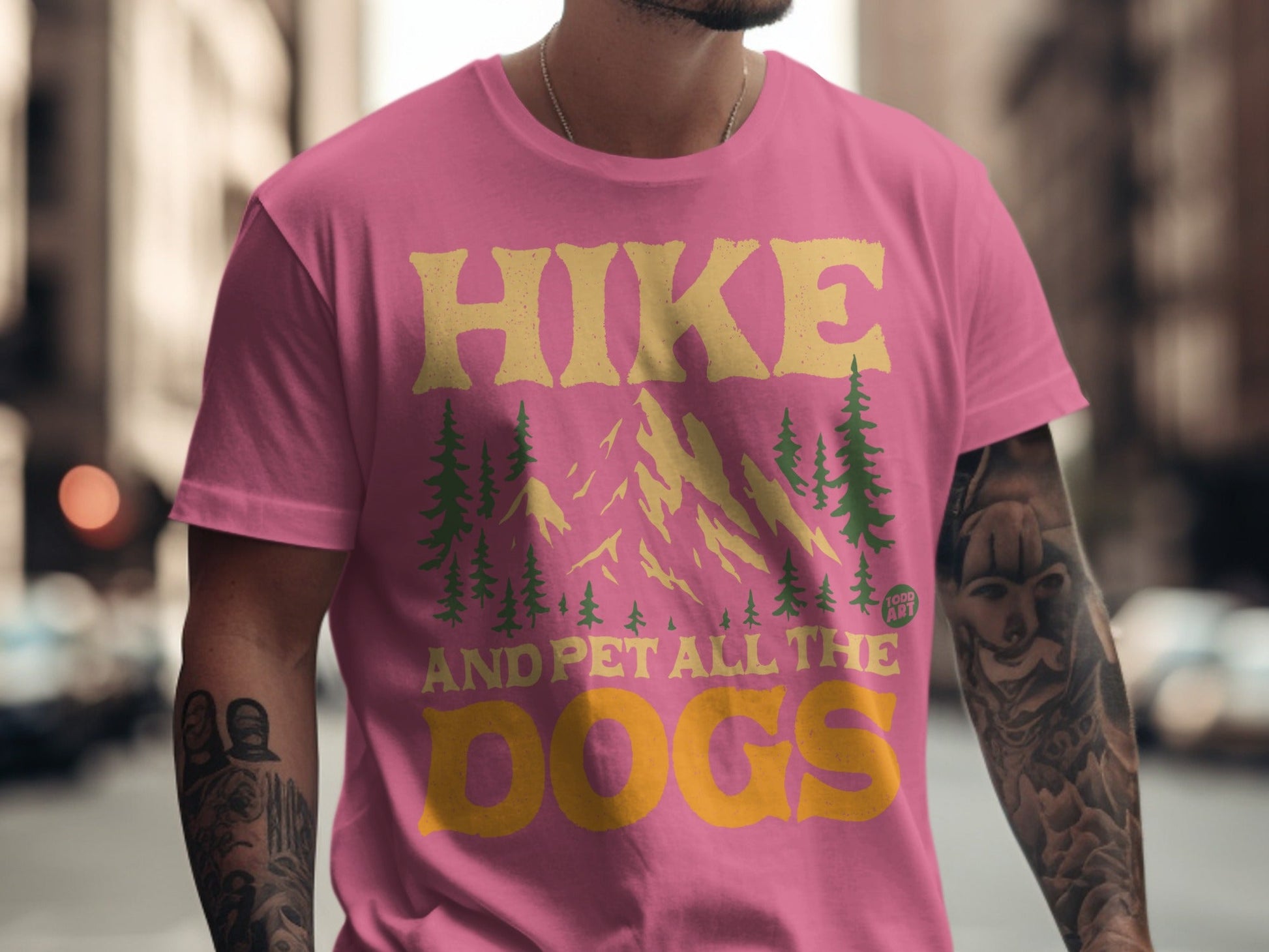 Pink t-shirt with "Hike and Pet All the Dogs" text and mountain graphic.