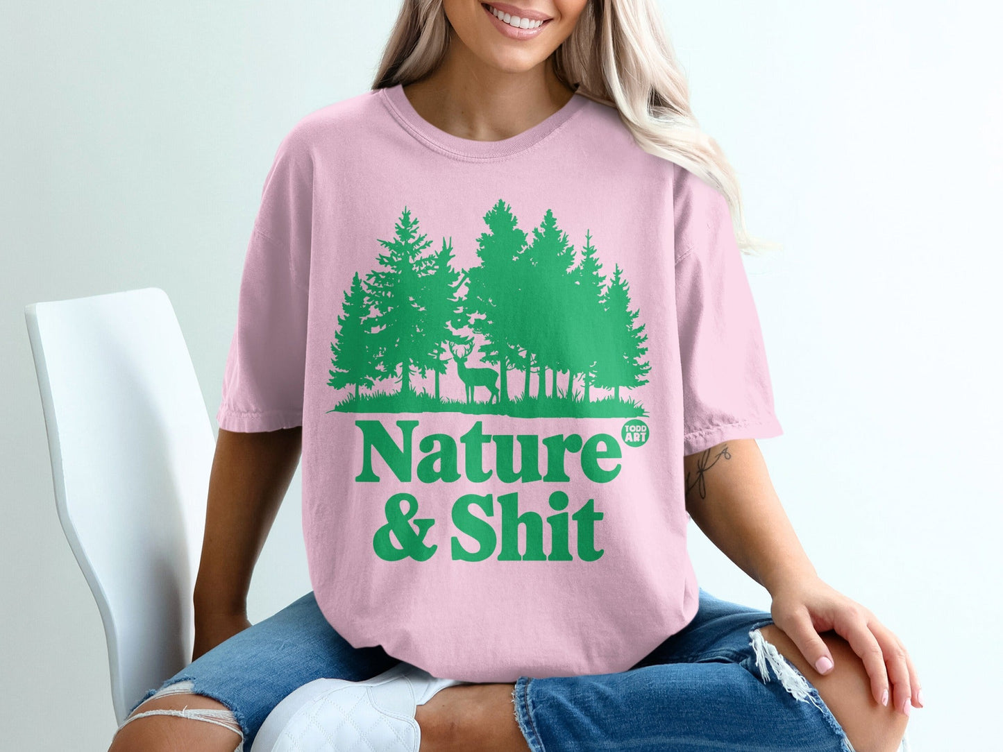 Pink t-shirt with green forest and deer graphic, text "Nature & Shit".
