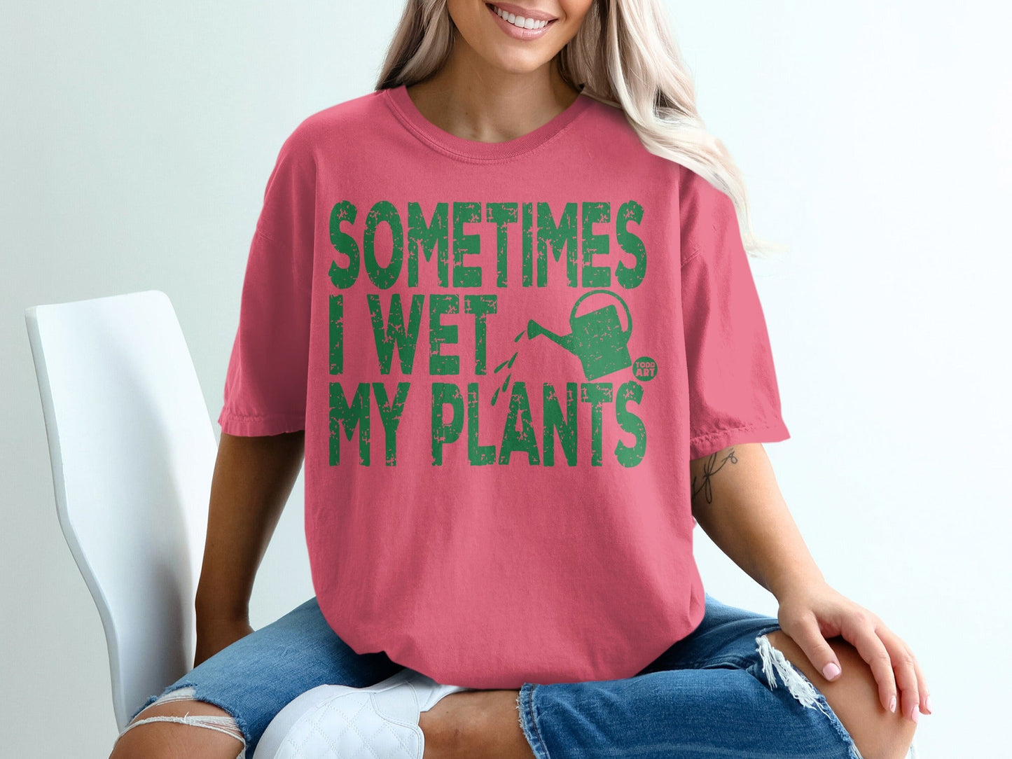 Pink t-shirt with green text "SOMETIMES I WET MY PLANTS" and a watering can graphic.