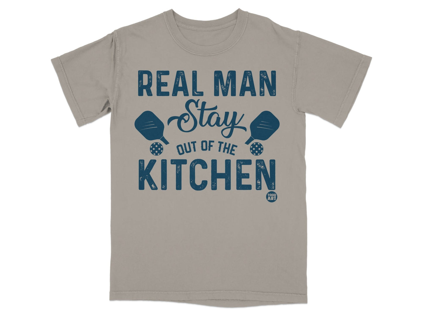 T-shirt with text "REAL MAN STAY OUT OF THE KITCHEN" and pickleball paddles.