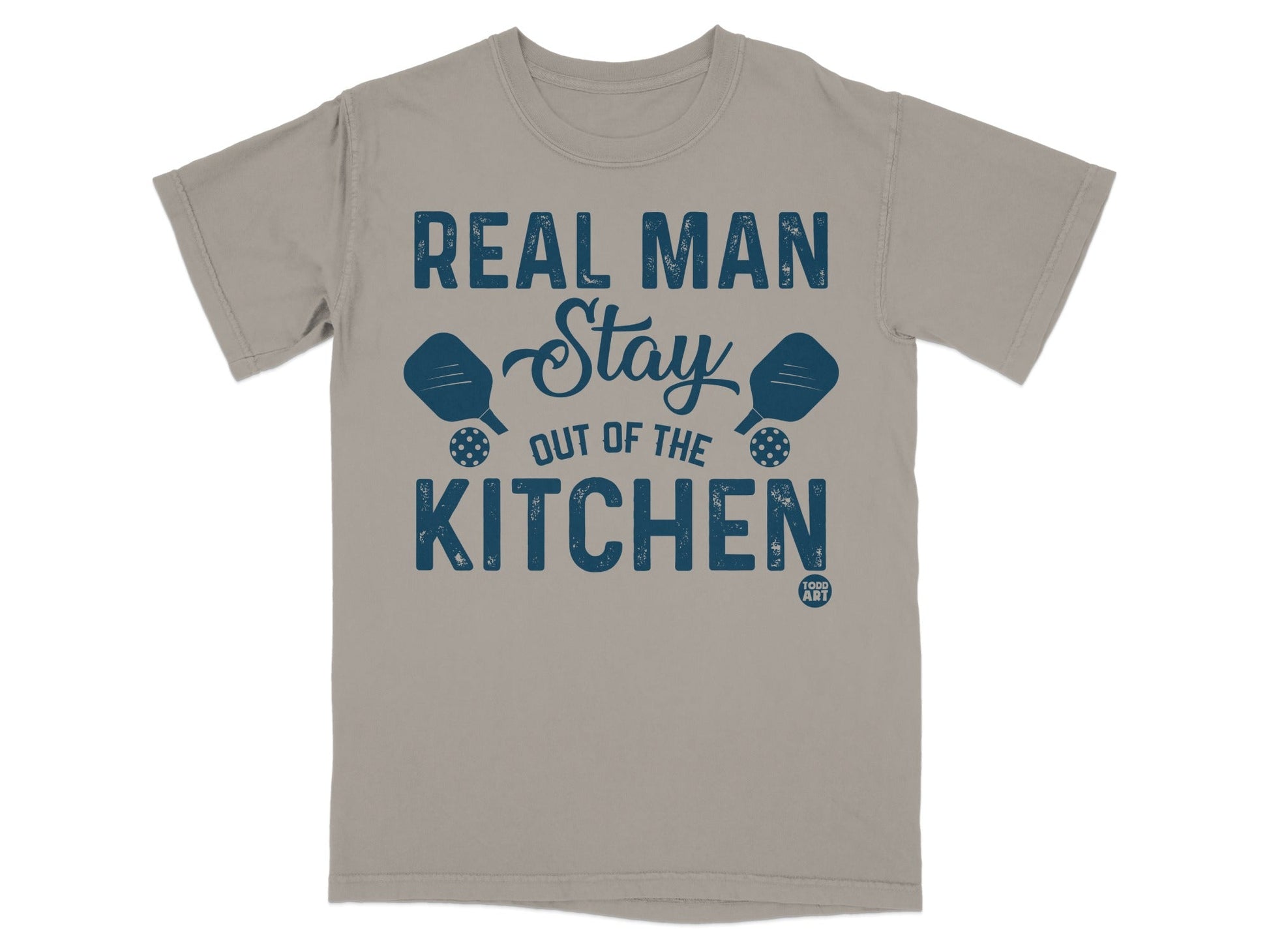 T-shirt with text "REAL MAN STAY OUT OF THE KITCHEN" and pickleball paddles.