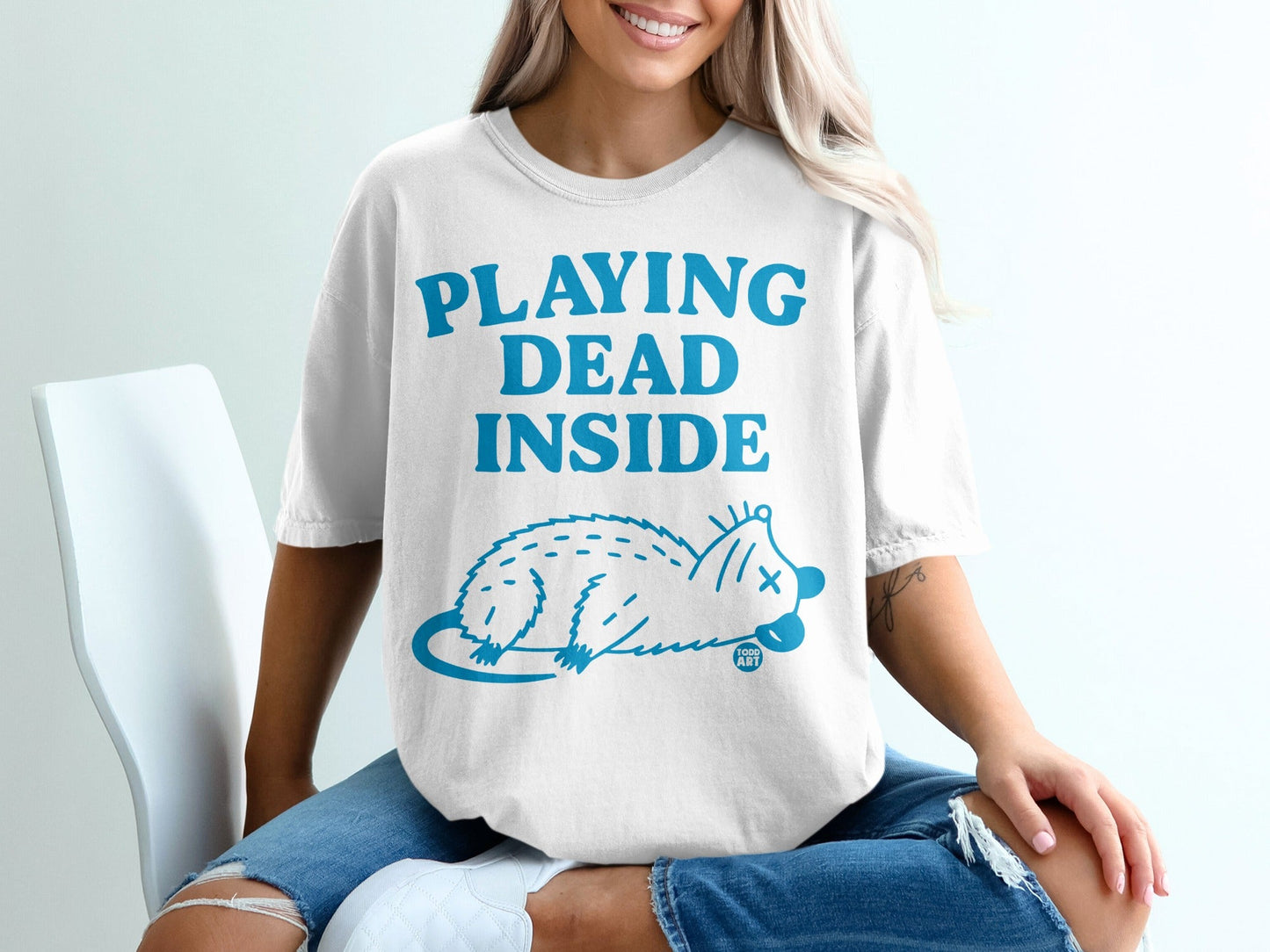 White t-shirt with "PLAYING DEAD INSIDE" and a stylized opossum graphic.
