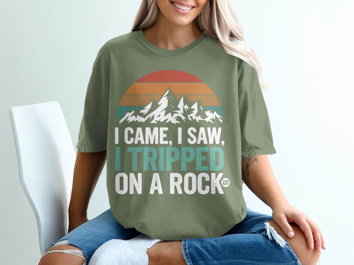 Green t-shirt with mountains and text "I came, I saw, I tripped on a rock".