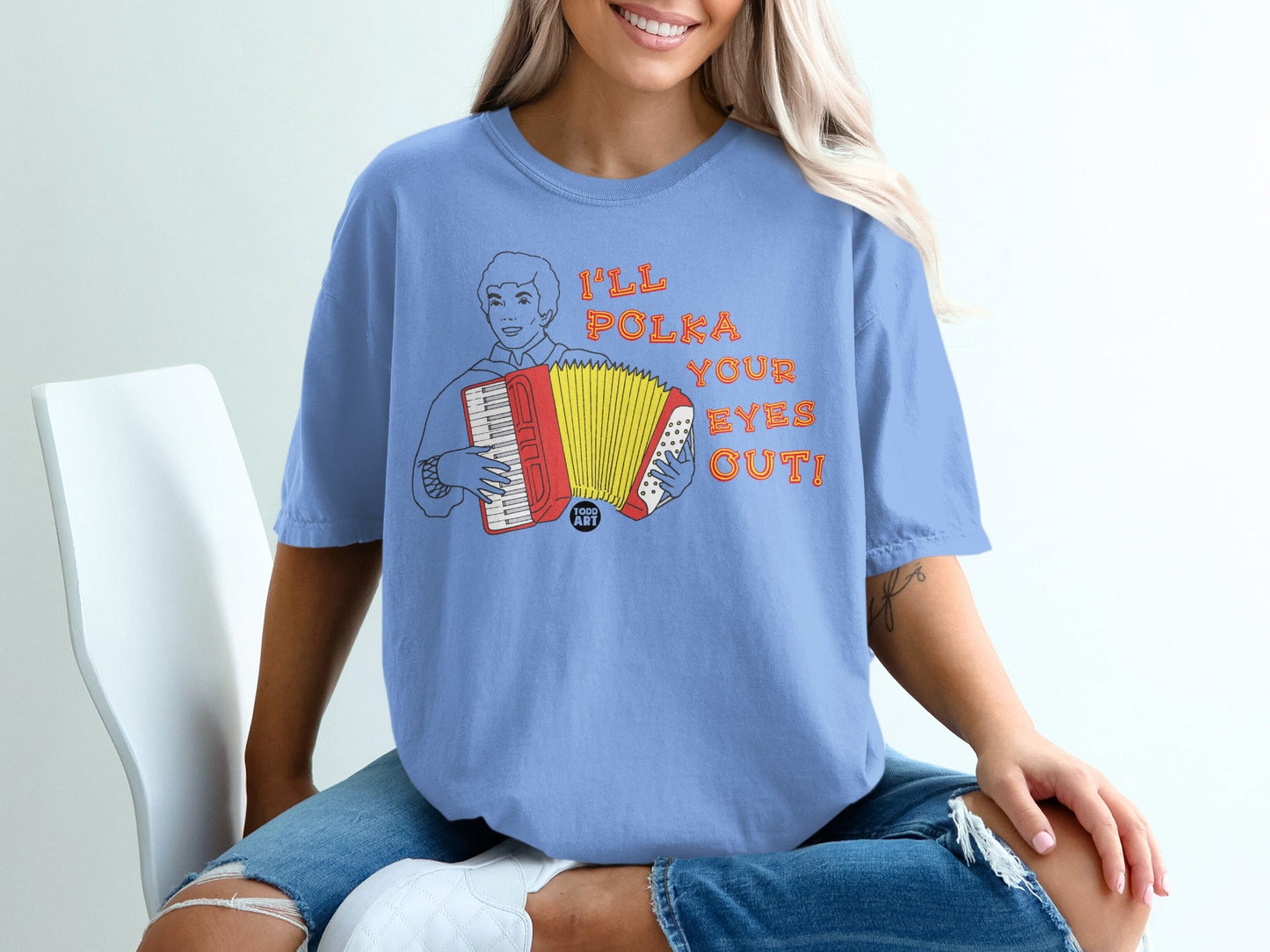 Blue t-shirt with a cartoon man playing an accordion and the text "I'LL POLKA YOUR EYES OUT!".