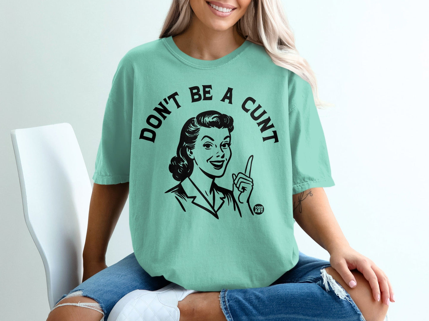 Mint green t-shirt with black graphic of a woman saying "Don't Be A Cunt".