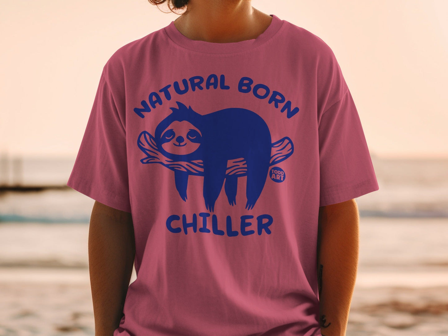 Pink t-shirt with blue text and sloth illustration: Natural Born Chiller.