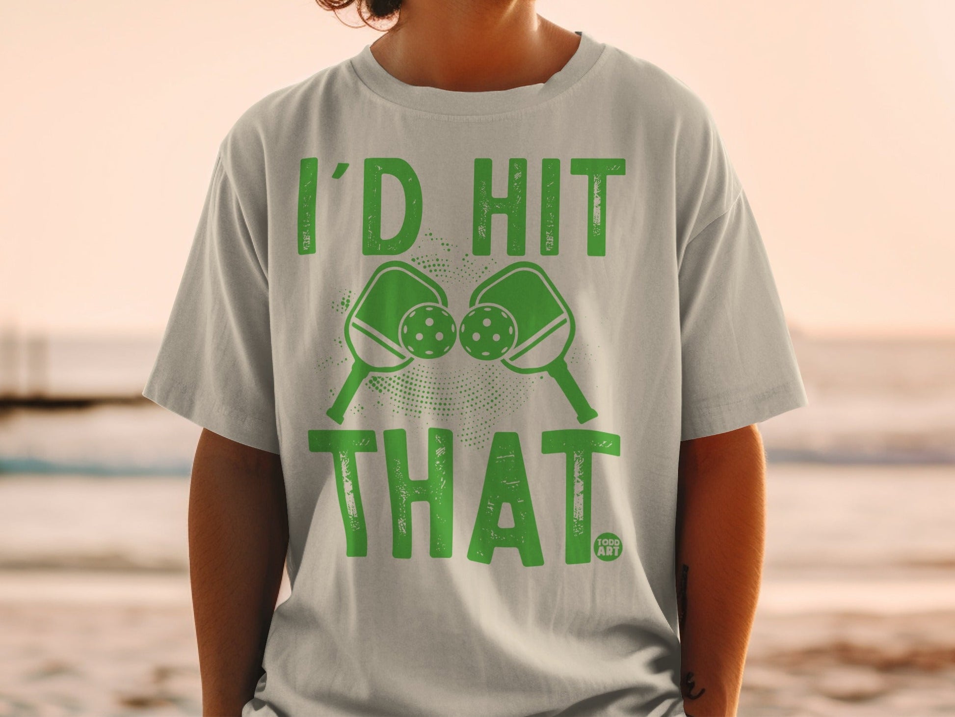 Green t-shirt with pickleball paddles and balls, "I'd Hit That" text.
