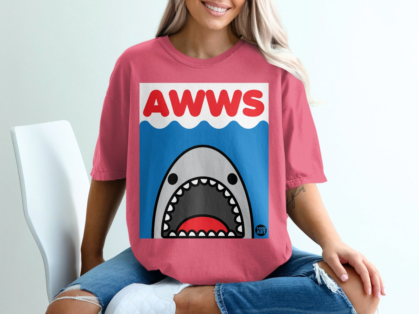 Pink t-shirt with cartoon shark and "AWWS" text on white background.