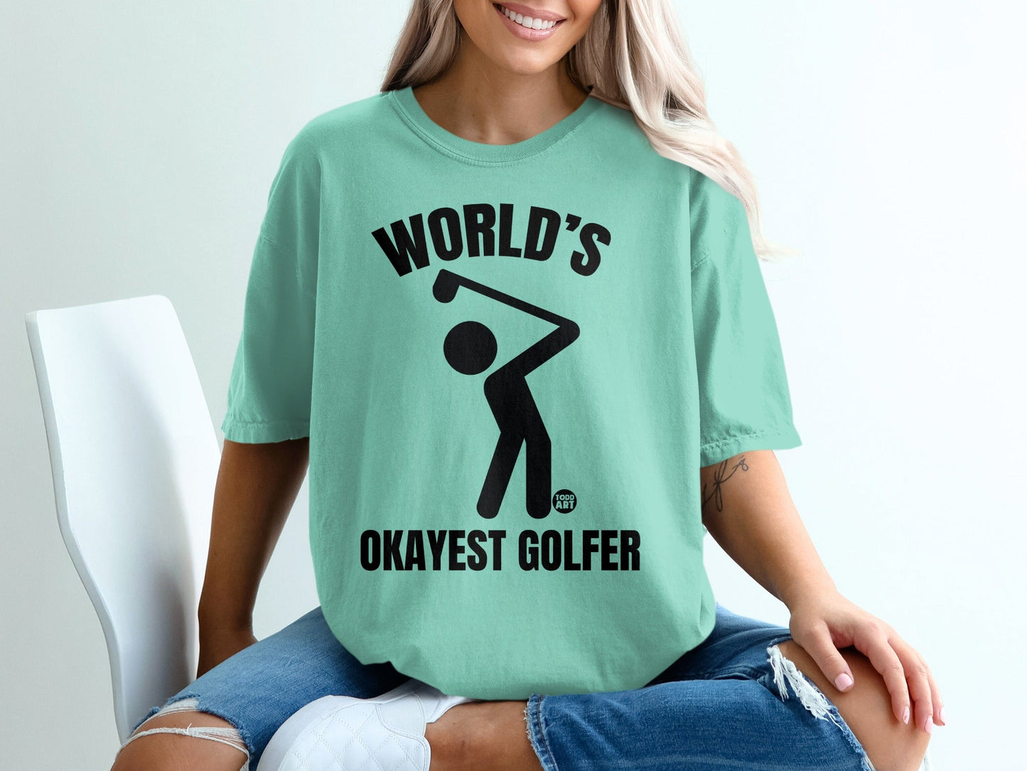 Mint green t-shirt with "World's Okayest Golfer" text and a golfer silhouette.
